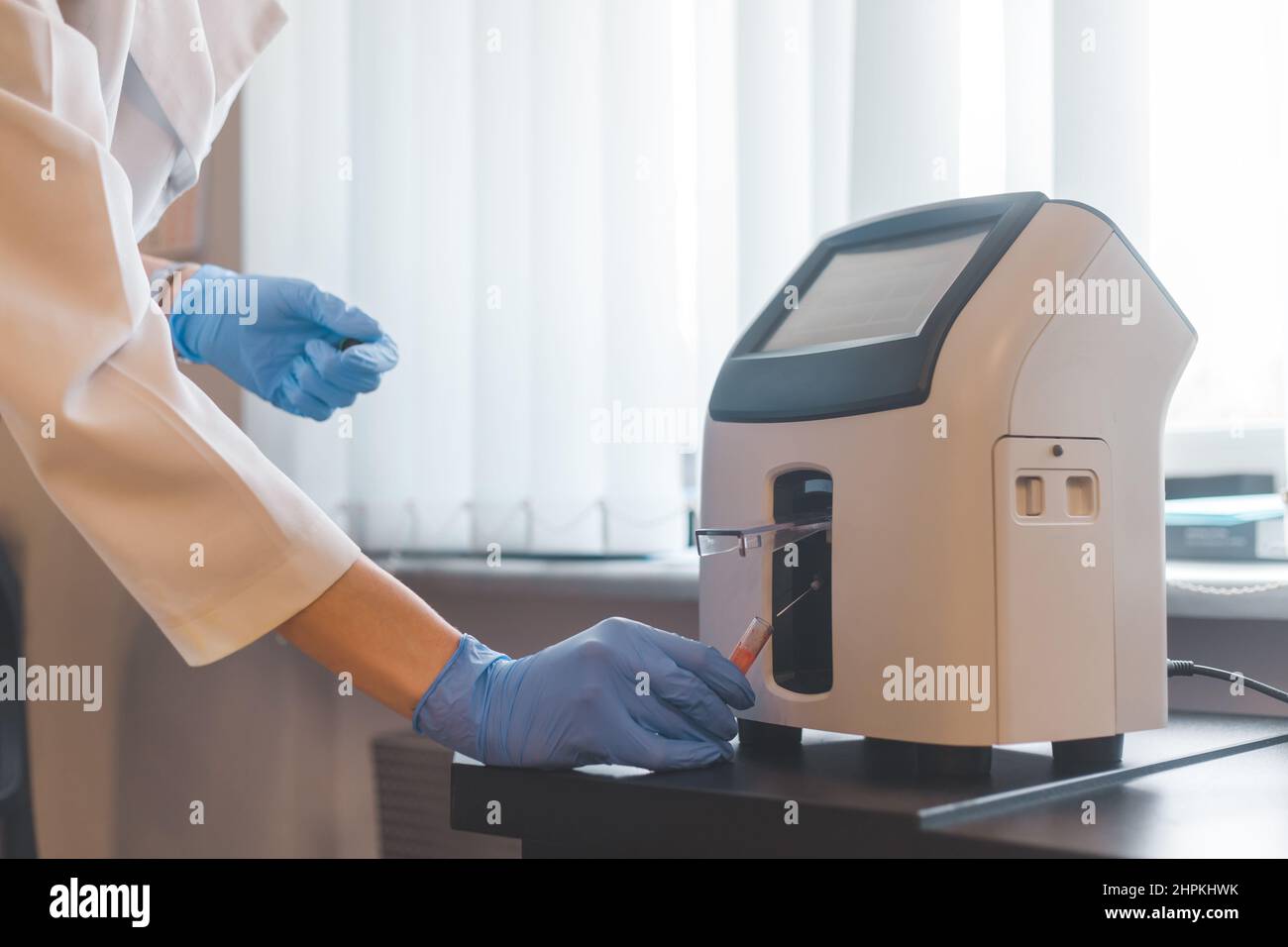 Laboratory worker inserts blood tube into animal electrolyte analyzer. Stock Photo