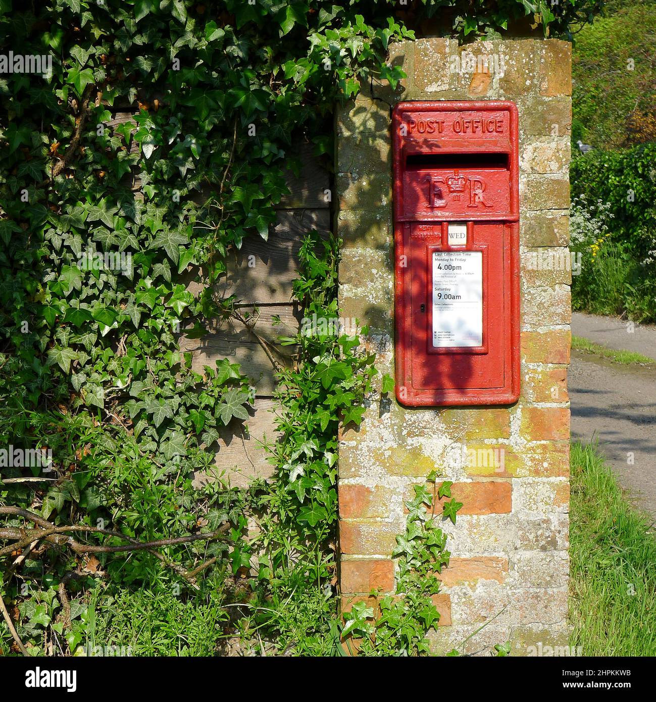 Traditional Red letter box built into an old wall, covered in ivy, in a