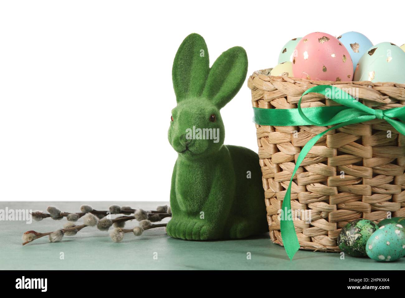 Basket with painted Easter eggs, willow branches and bunny on table ...