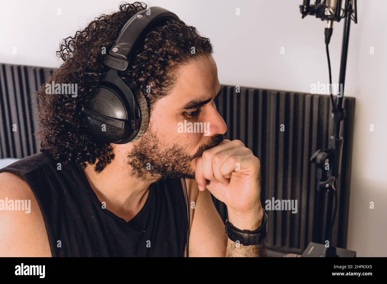 closeup of caucasian young man touching his lips thinking and staring, inside his home recording studio, music industry concept. Stock Photo