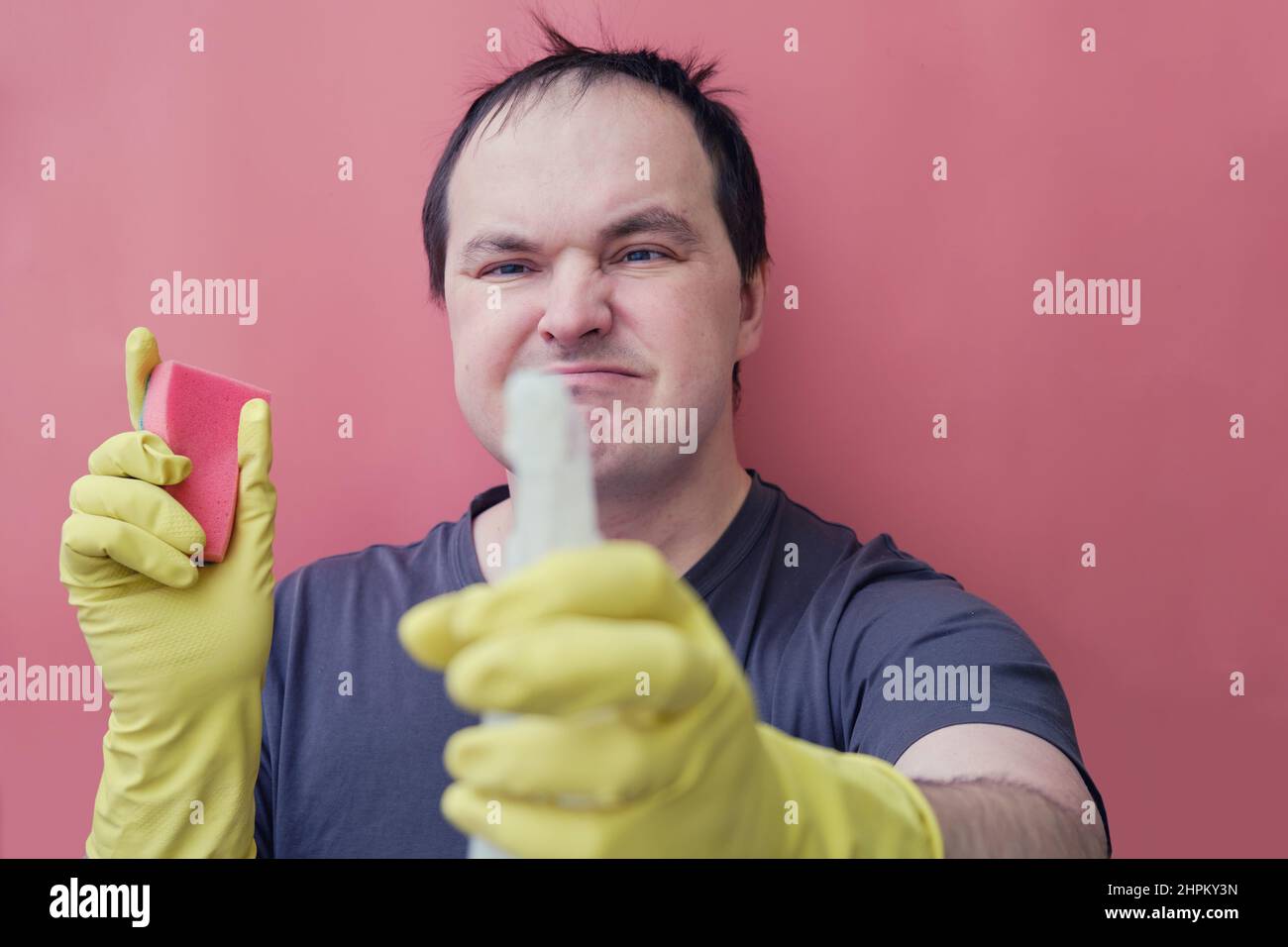 Angry man janitor in yellow gloves, studio red background Stock Photo