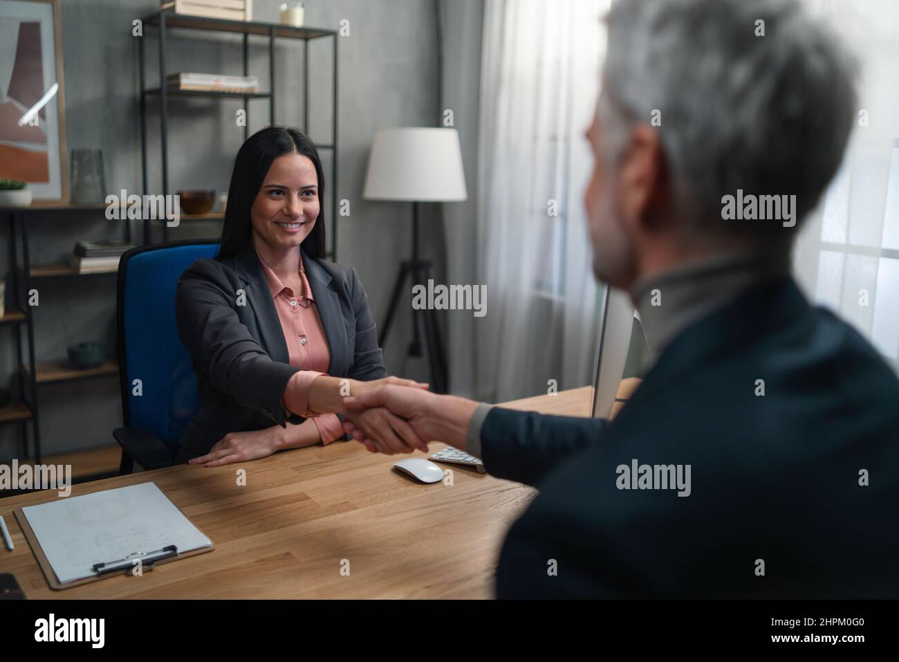 A financial advisor shaking hand with her client indoors in office. Stock Photo