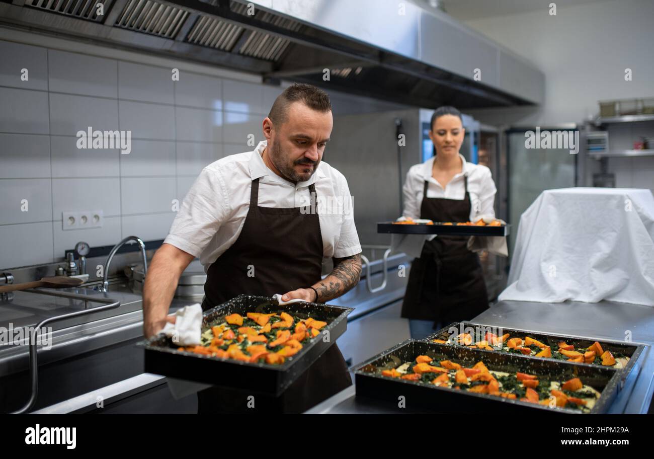 Chef and cook working on their dishes indoors in restaurant kitchen ...