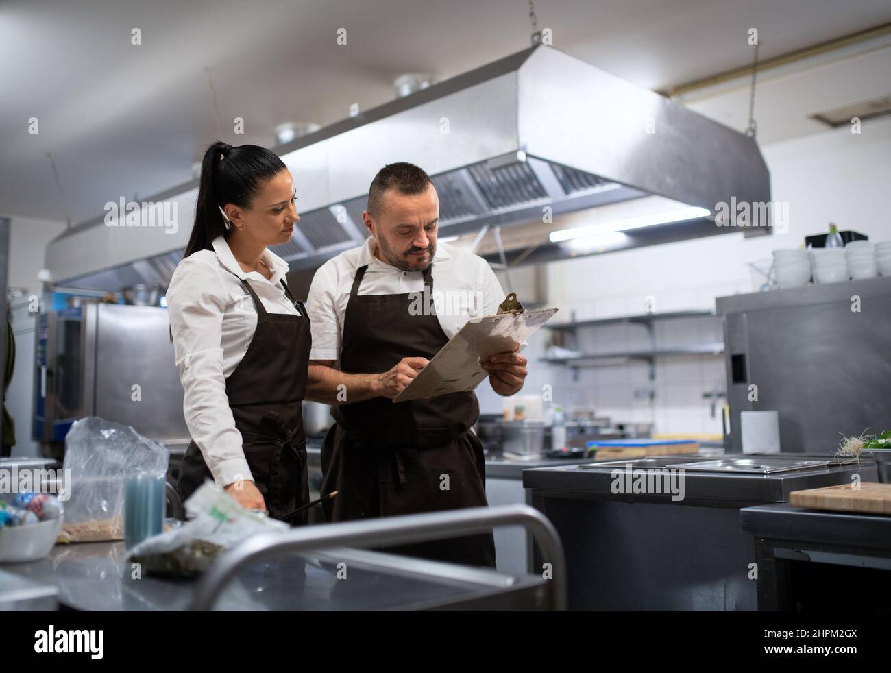 Chef and cook discussing menu indoors in restaurant kitchen Stock Photo ...