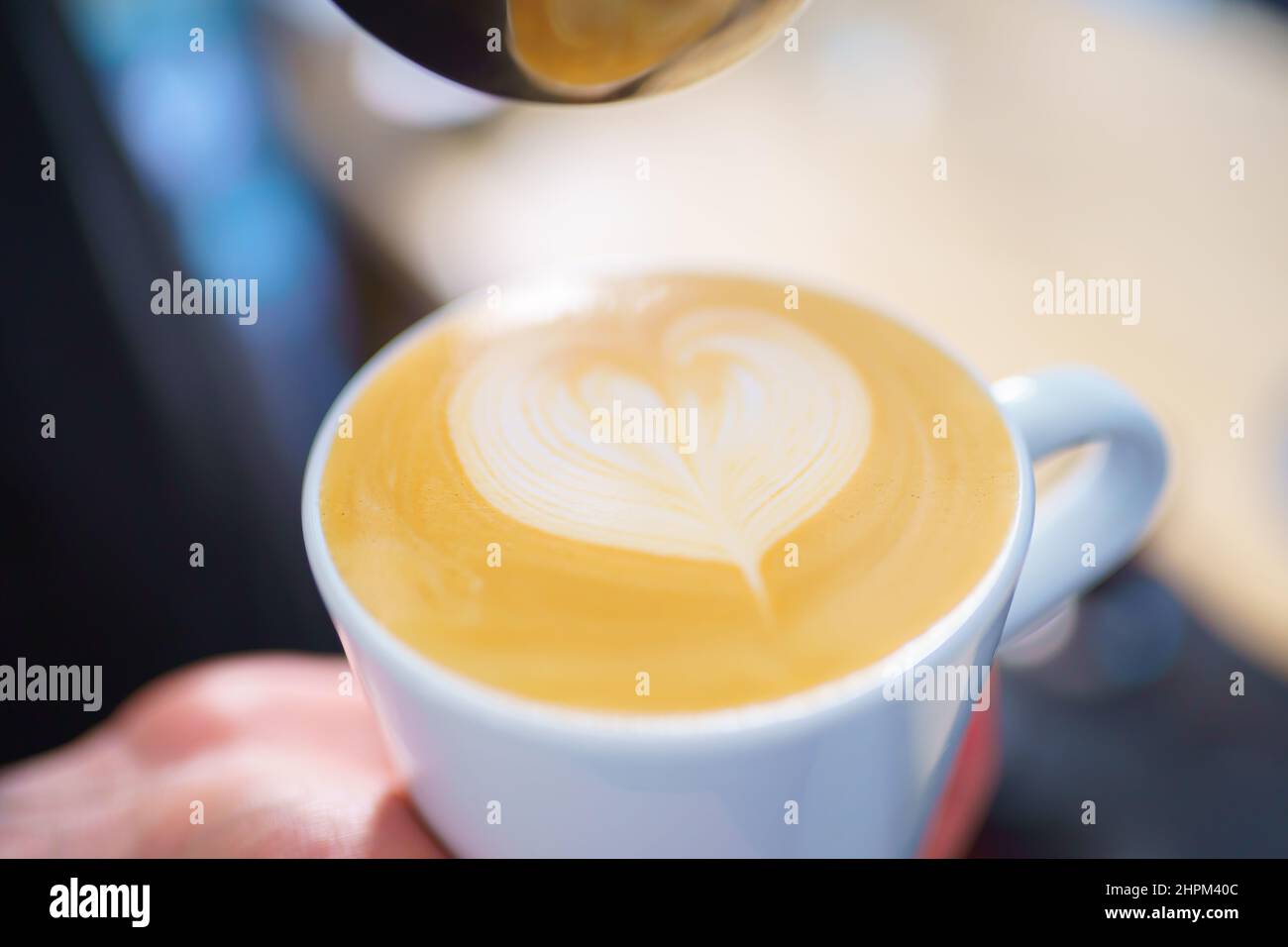 barista pouring milk into espresso coffee for making cappuccino, latte