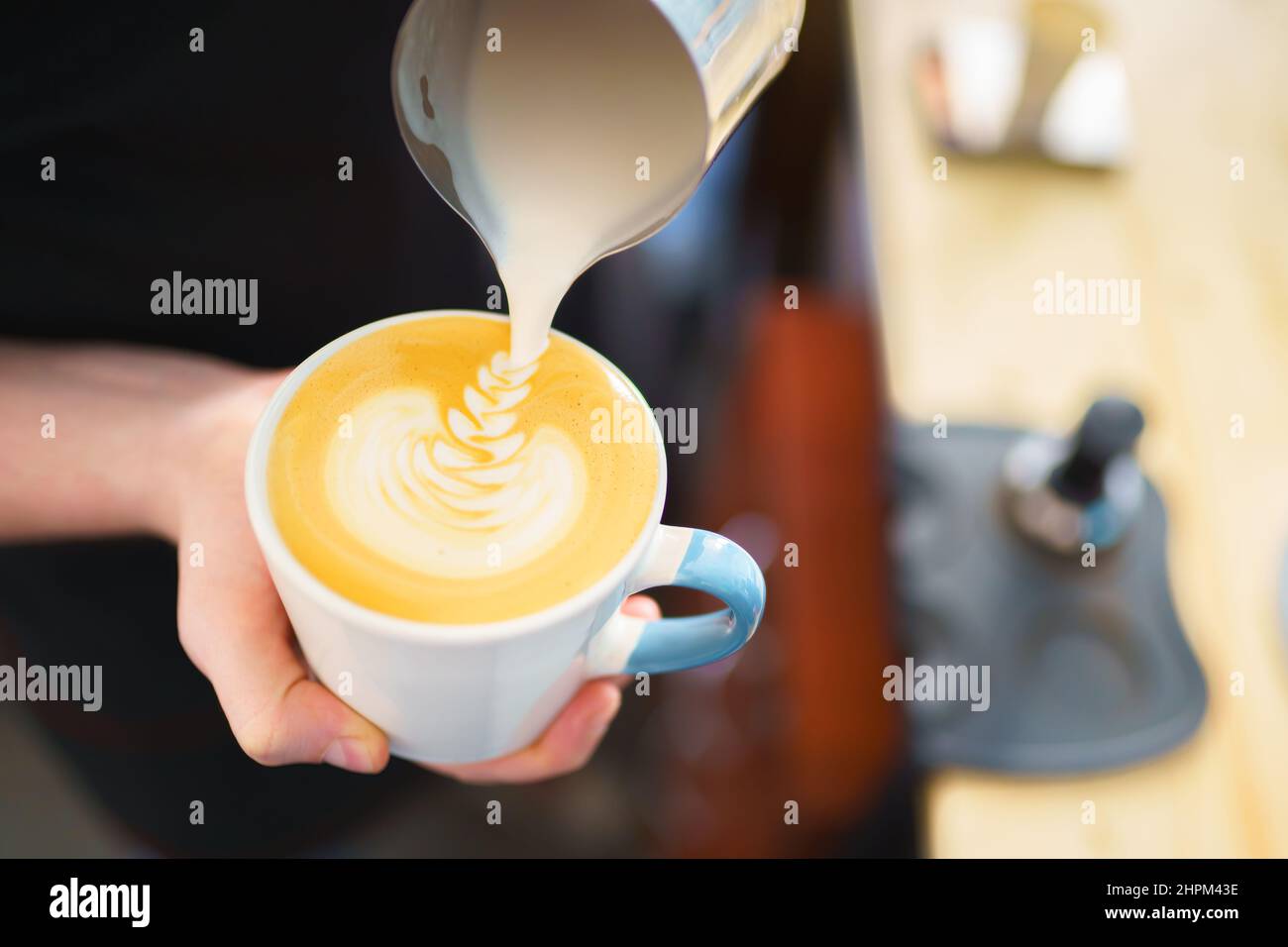 barista pouring milk into espresso coffee for making cappuccino, latte