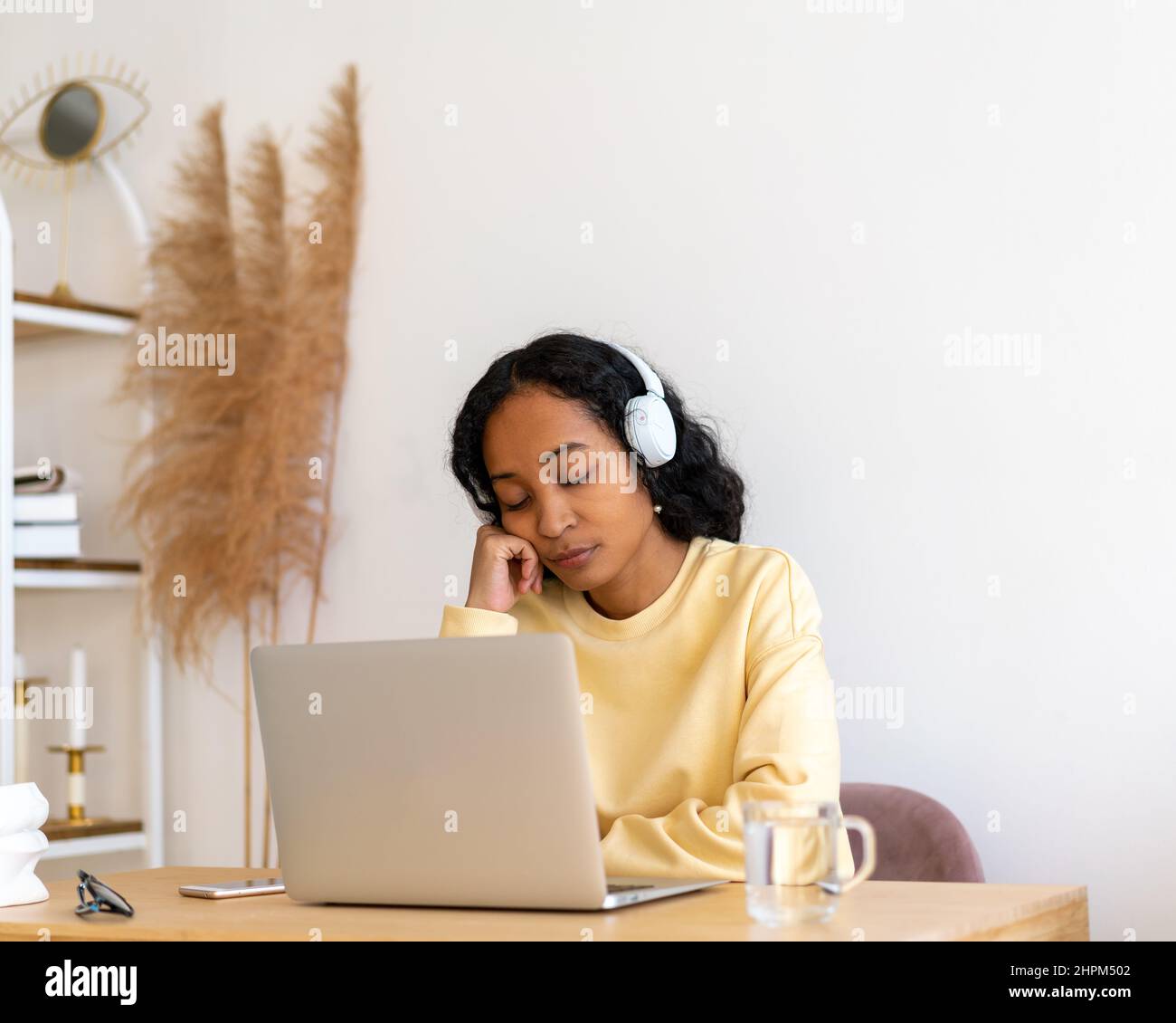 Bored african-american female student sleeping during online classes on laptop at home Stock Photo