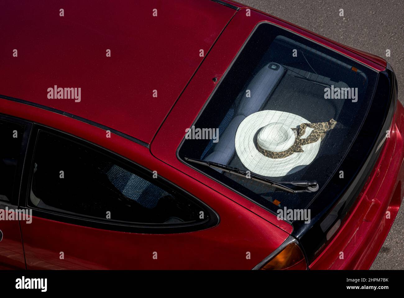 White straw sun hat on the parcel shelf of a red car, seen from above, Playa de San Juan, Tenerife, Canary Islands, Spain Stock Photo