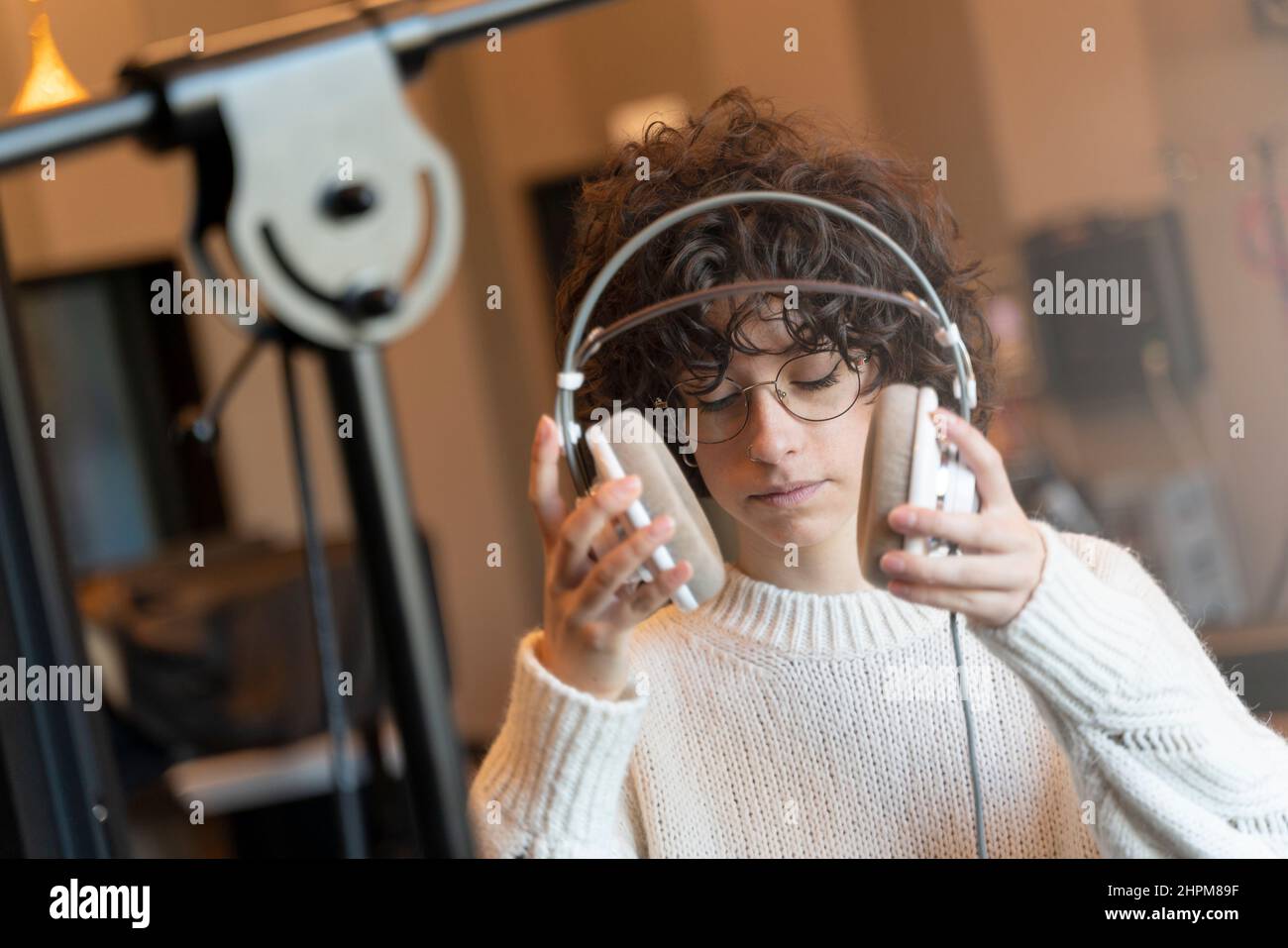 A young curly hair singer woman with glasses recording a song in a real