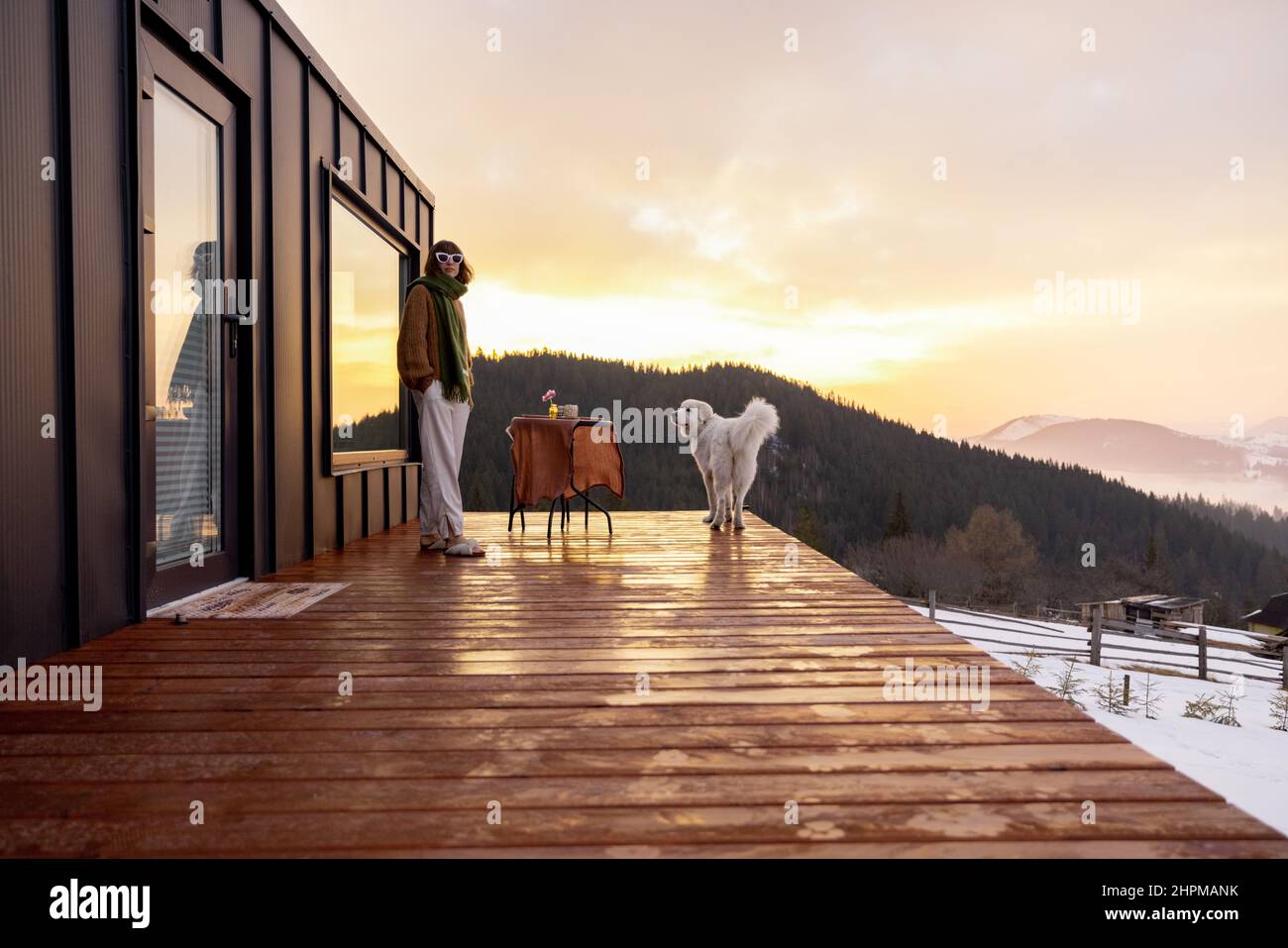 Woman with her dog resting on terrace of tiny house on nature Stock ...