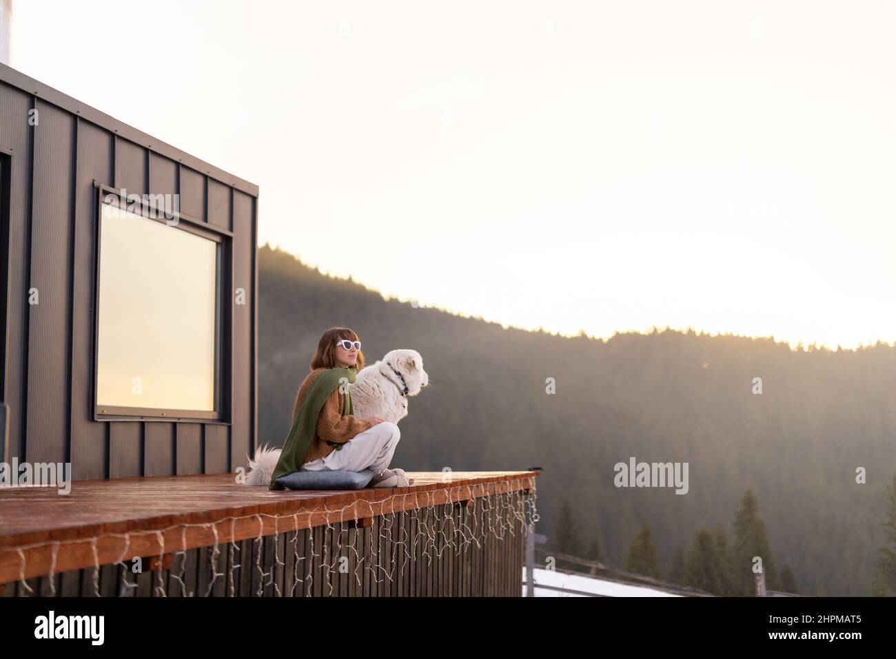 Woman with her dog resting on terrace of tiny house on nature Stock ...