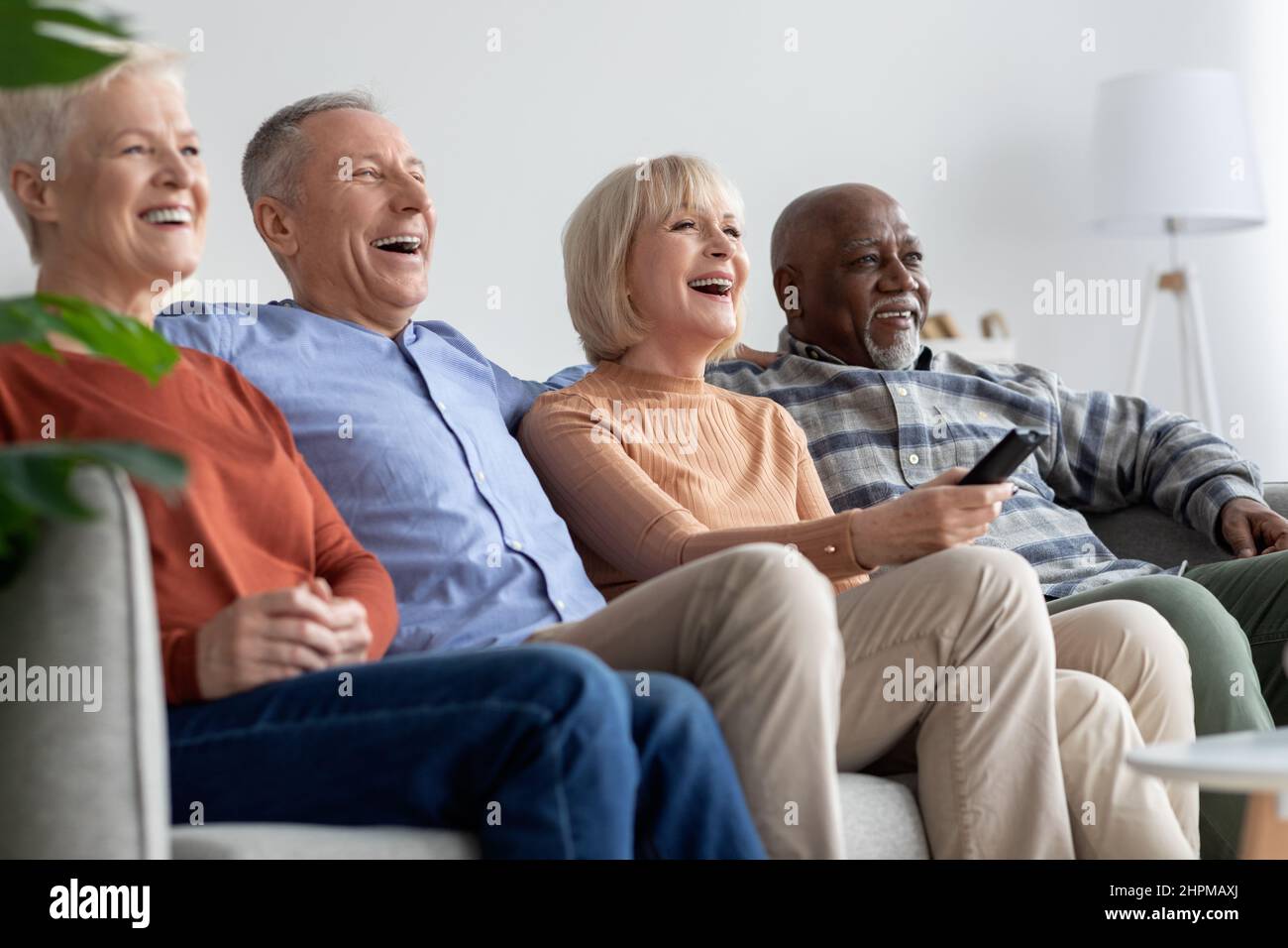 Multiracial friends senior people watching TV and laughing Stock Photo