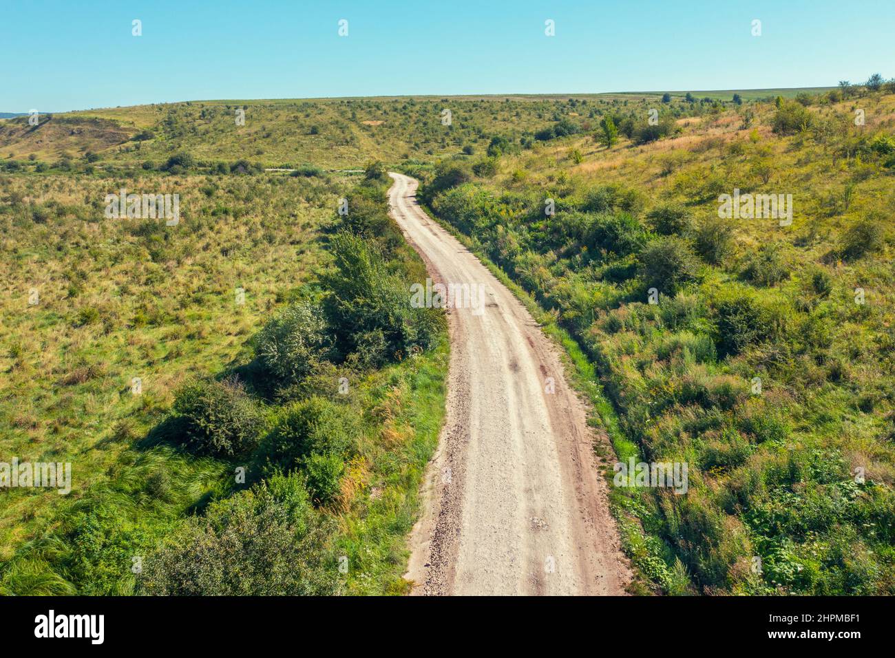 Top view of country dirt road between hills on a summer sunny day Stock Photo