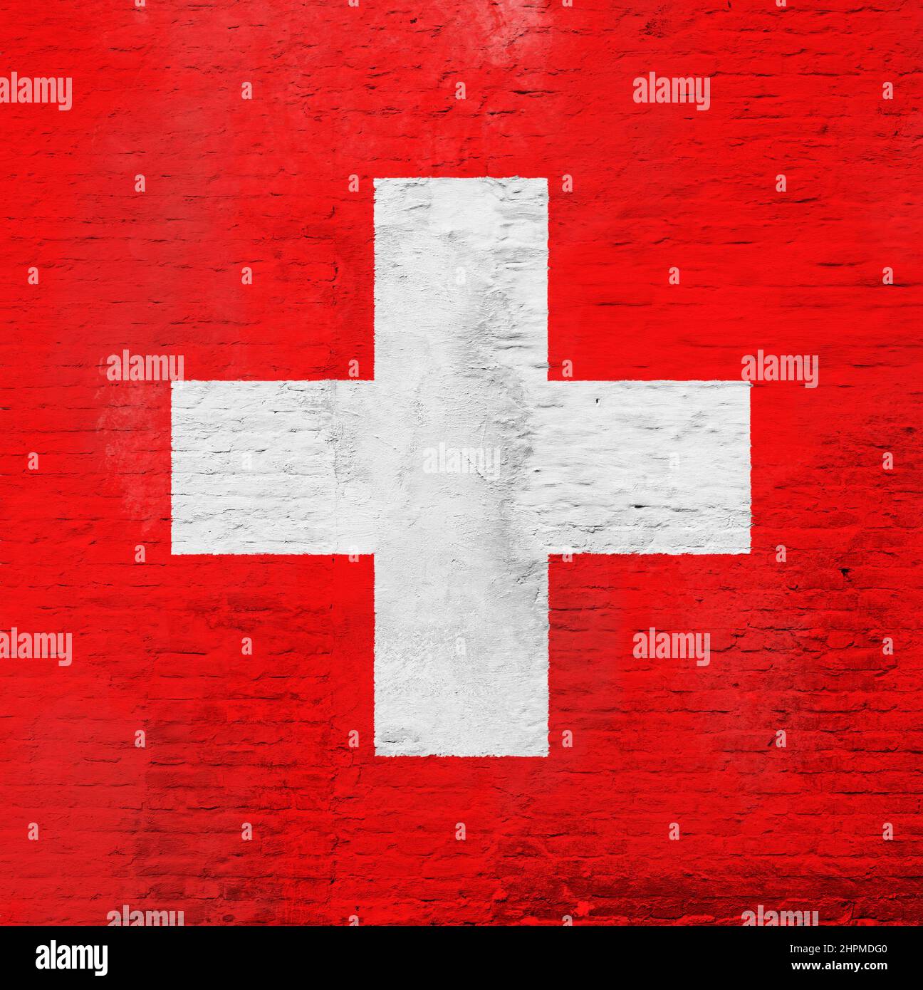 Full frame photo of a weathered flag of Switzerland painted on a plastered brick wall. Stock Photo