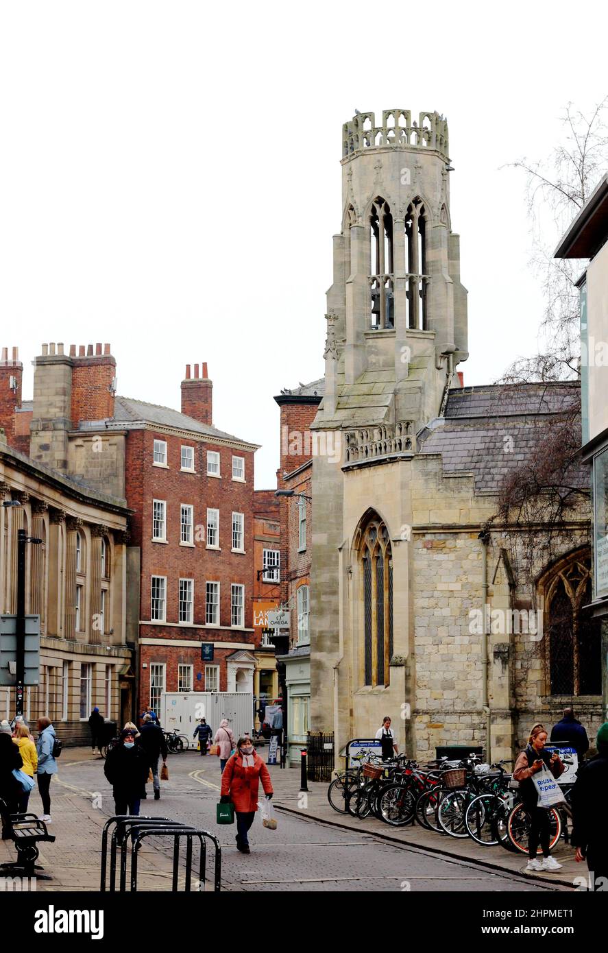 Shoppers walking along Davygate on a grey day in York, next to the Grade II Listed St Helen's Church Stock Photo