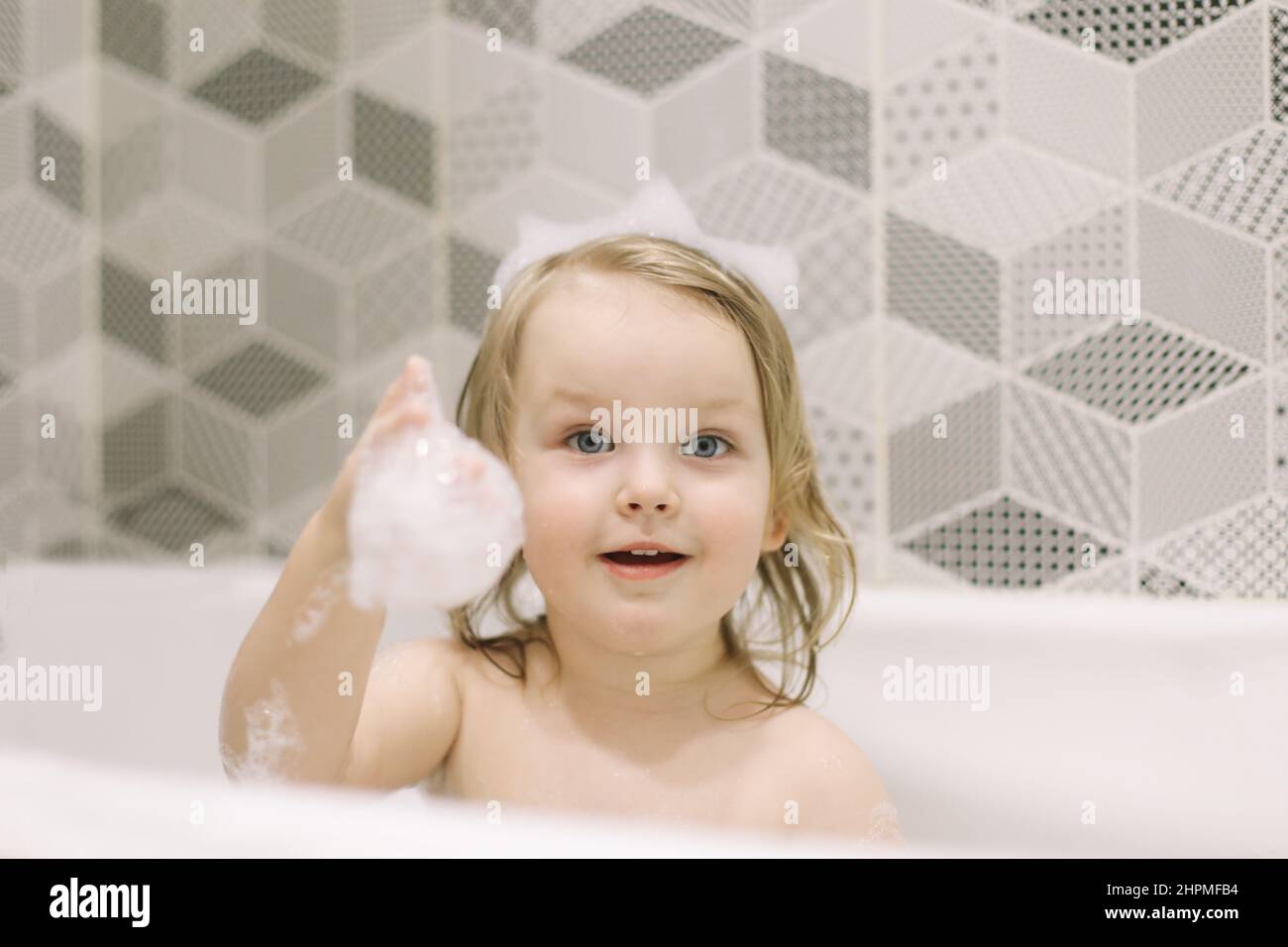 Child bathing. Little baby taking bath, closeup face portrait of smiling girl, health care and kids hygiene. Stock Photo