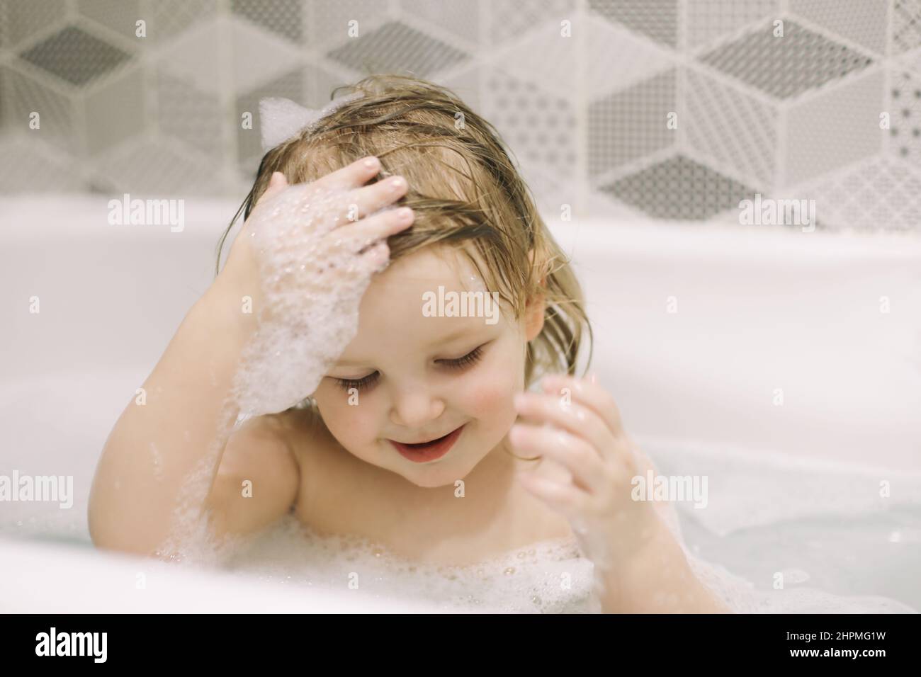 Child bathing. Little baby taking bath, closeup face portrait of