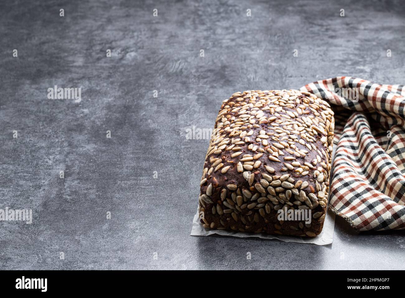 Homemade dark rye bread with sunflower seeds on gray stone background