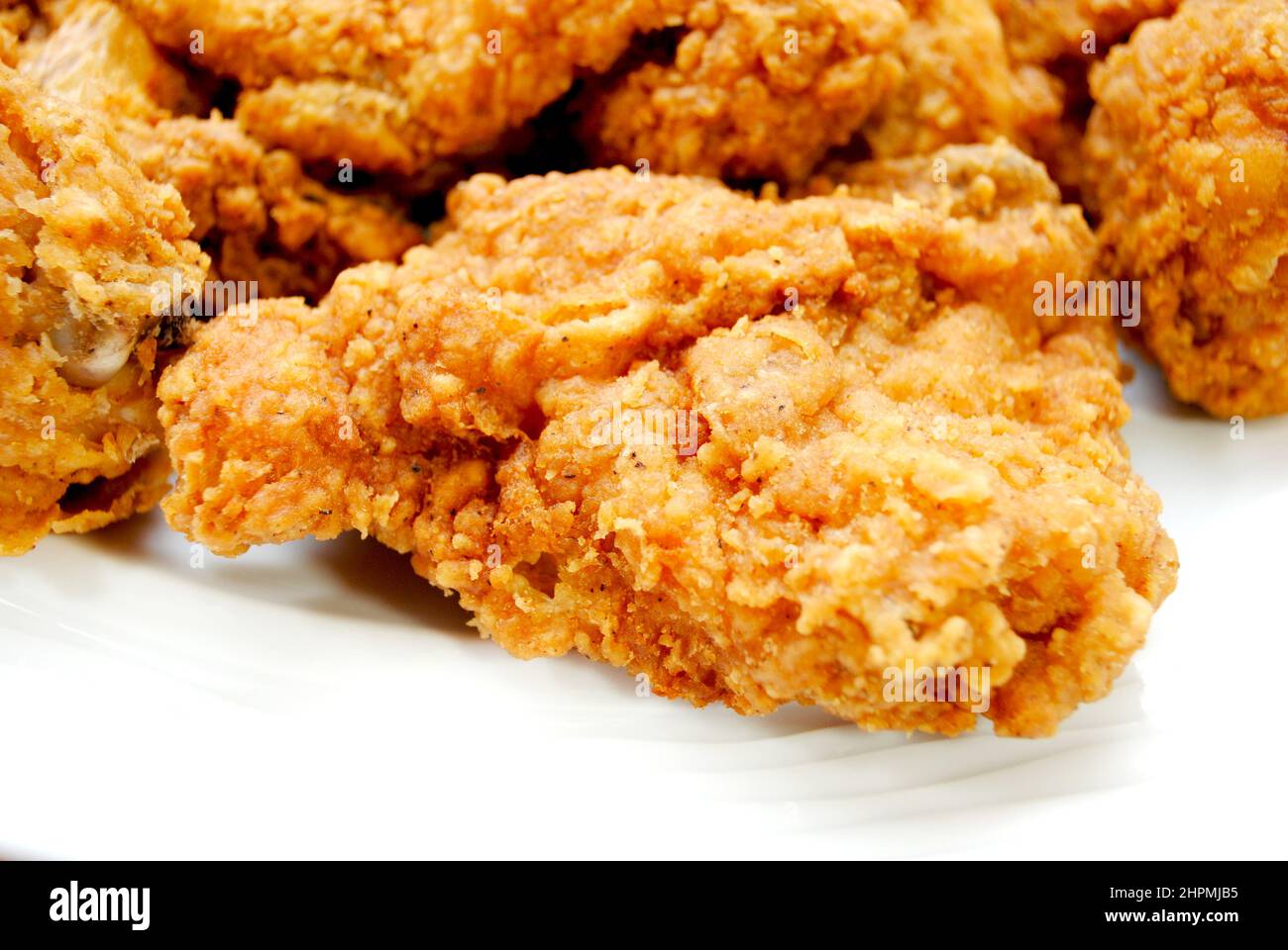 Close Up of a Southern Fried Chicken Thigh on a White Plate Stock Photo