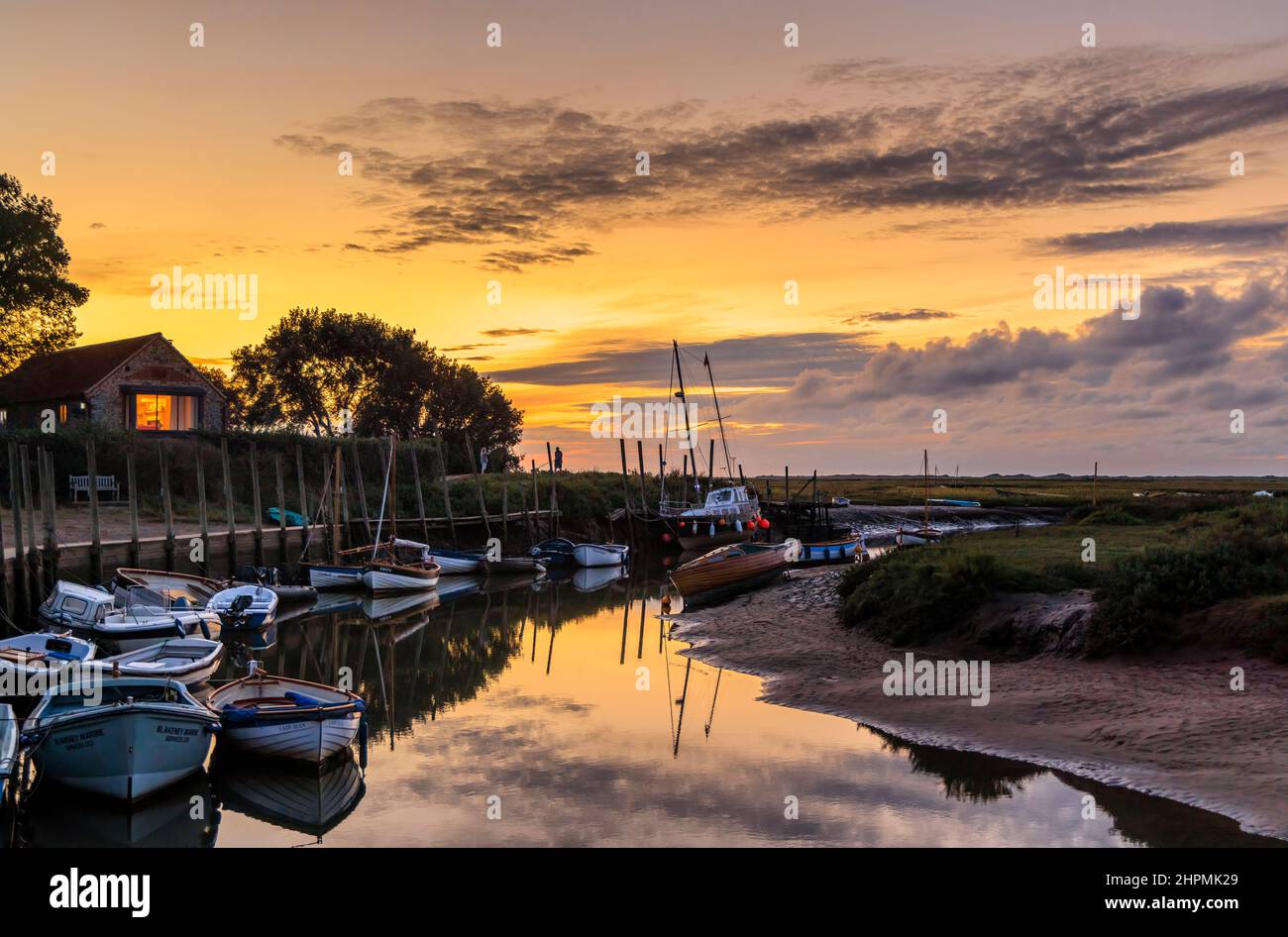 Dusk on the River Glaven estuary at low tide with boats and cloud reflections, Blakeney, a small coastal village in north coast Norfolk, England Stock Photo