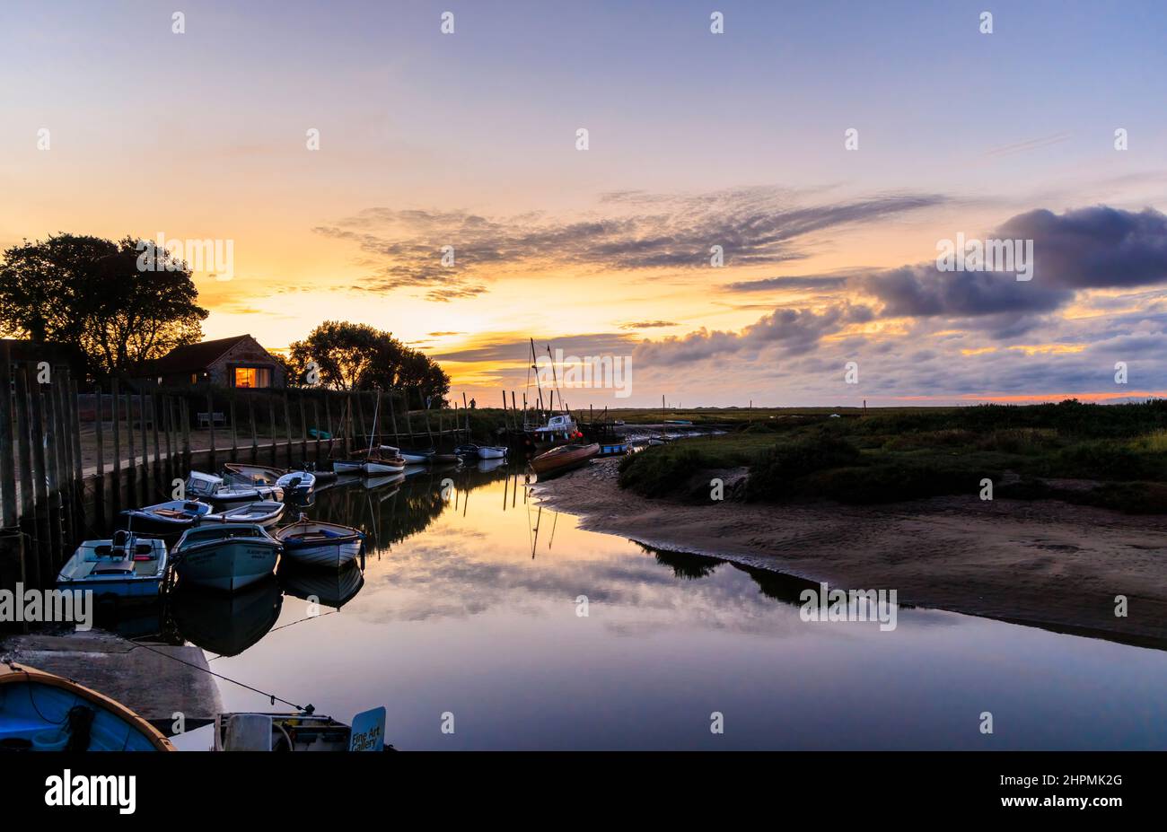 Dusk on the River Glaven estuary at low tide with boats and cloud reflections, Blakeney, a small coastal village in north coast Norfolk, England Stock Photo