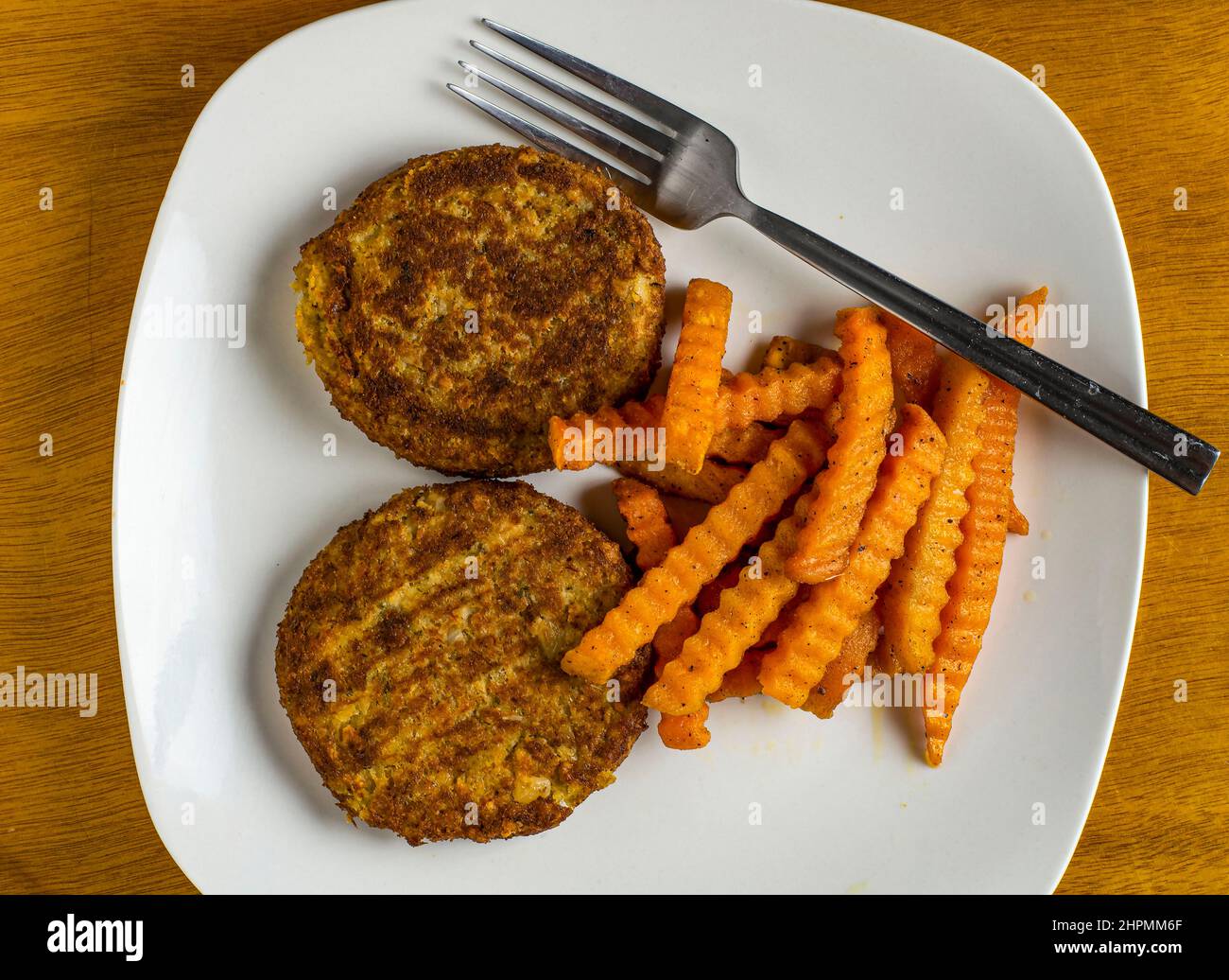 two crab cakes wide sweet potato fries on the side Stock Photo Alamy