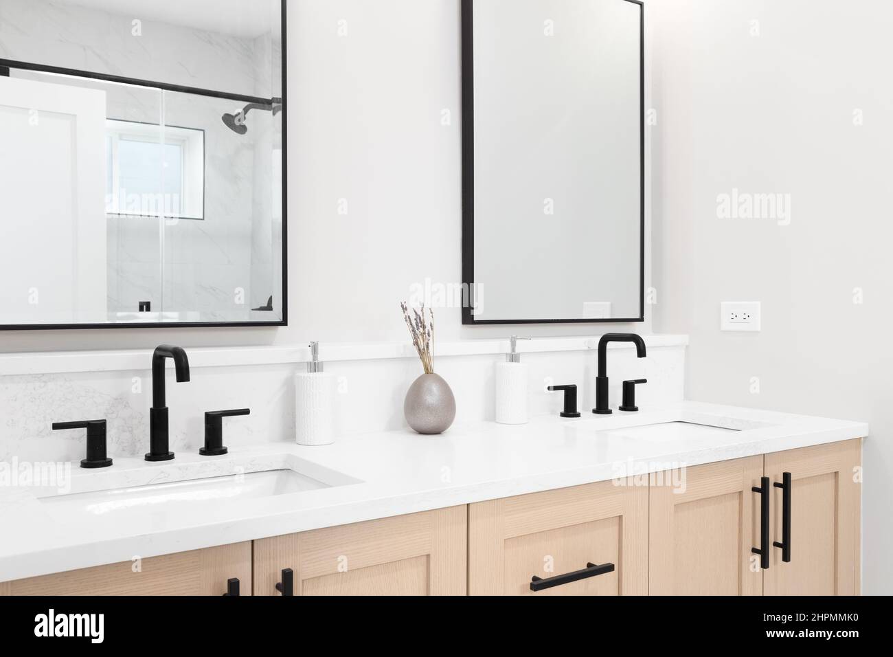 A modern bathroom with a wooden vanity black faucets, white