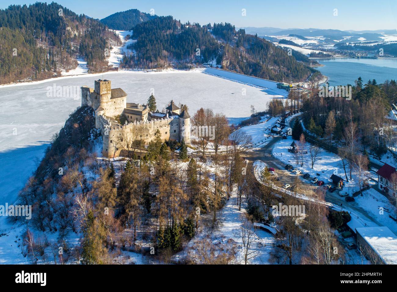 Poland. Medieval castle in Niedzica, dating back to 14th century (upper castle) in winter. Frozen artificial Czorsztyn lake on Dunajec river and a dam Stock Photo