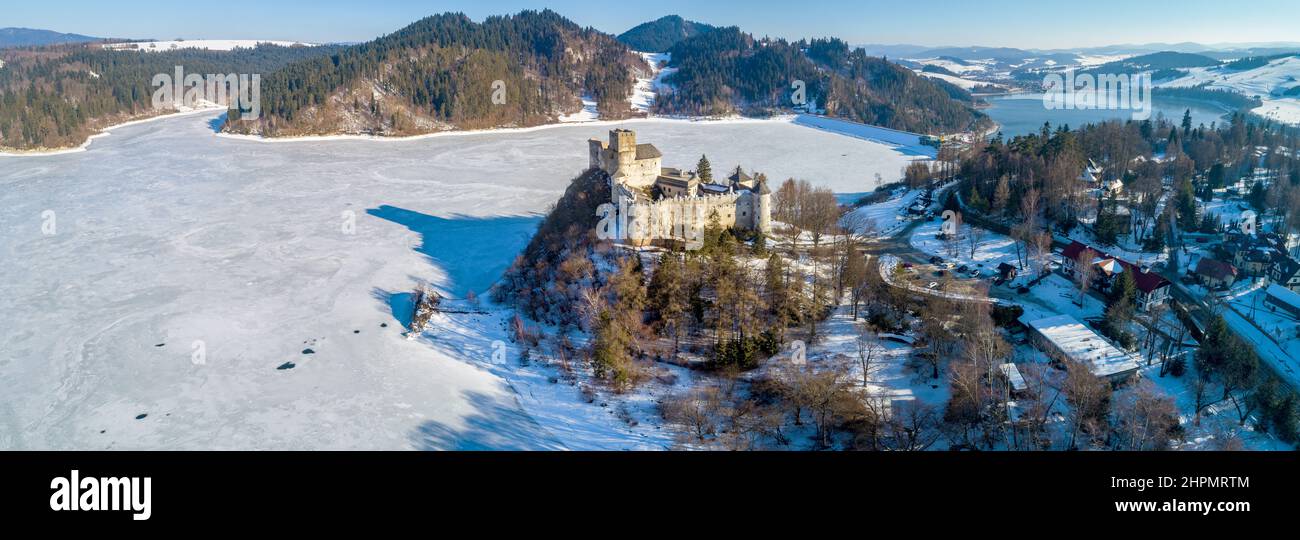 Poland. Wide aerial winter panorama of frozen artificial Czorsztyn lake with a dam and retention lake, medieval castle in Niedzica, dating back to 14t Stock Photo