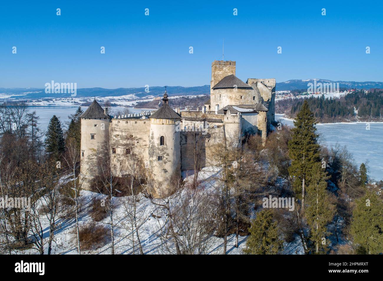 Poland. Medieval castle in Niedzica, dating back to 14th century (upper castle) in winter. Frozen artificial Czorsztyn lake on Dunajec river. Stock Photo