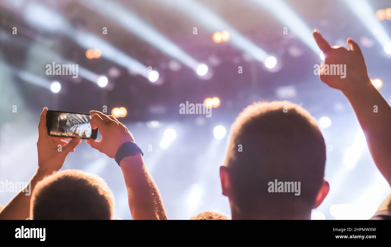 People recording video and showing devil horns gesture at rock concert ...