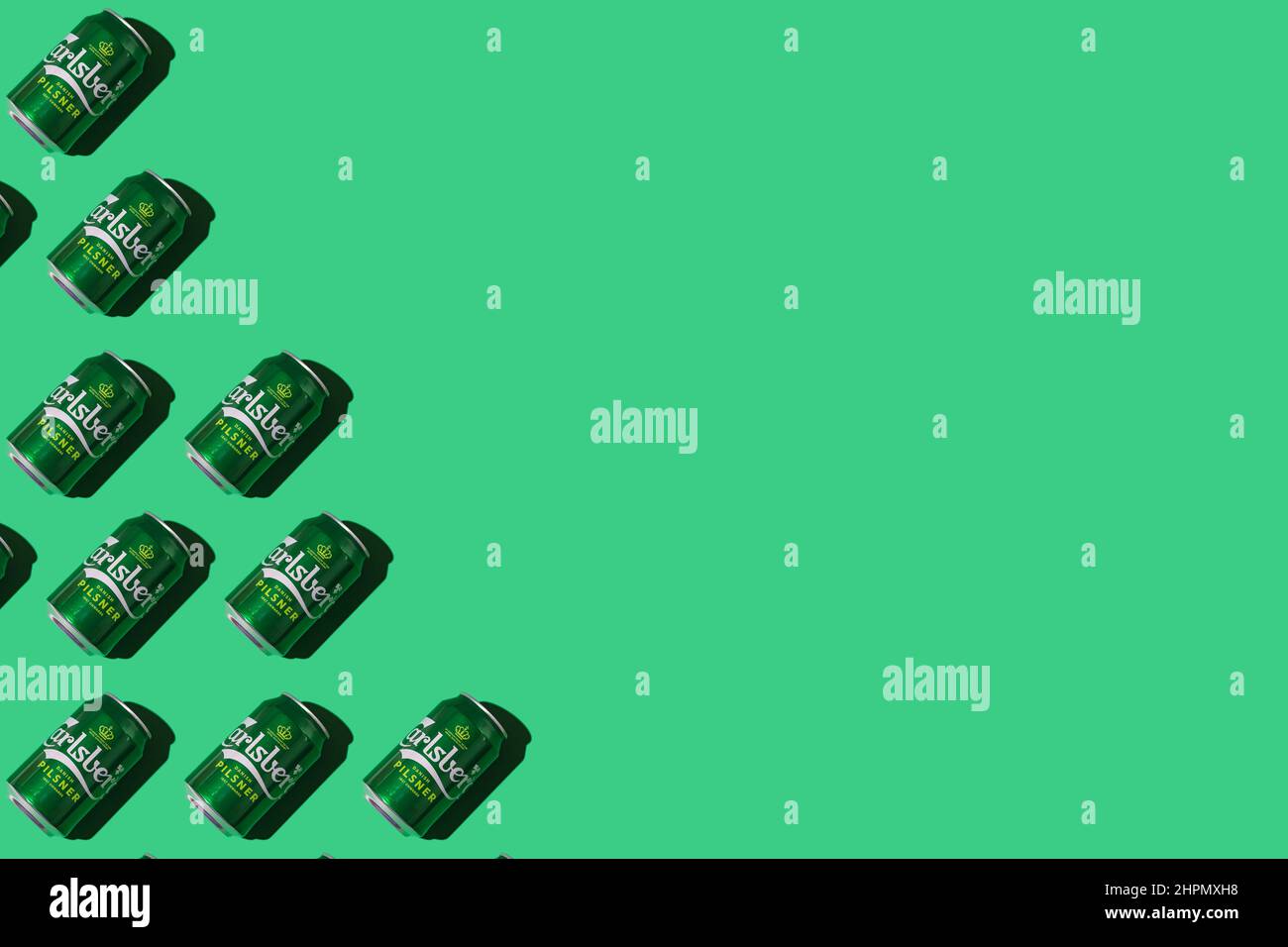 Pattern of green Heineken Dutch beer cans with hard shadow, on the left side, on white background. Alcohol, brewery, industry, factory and bar concept Stock Photo