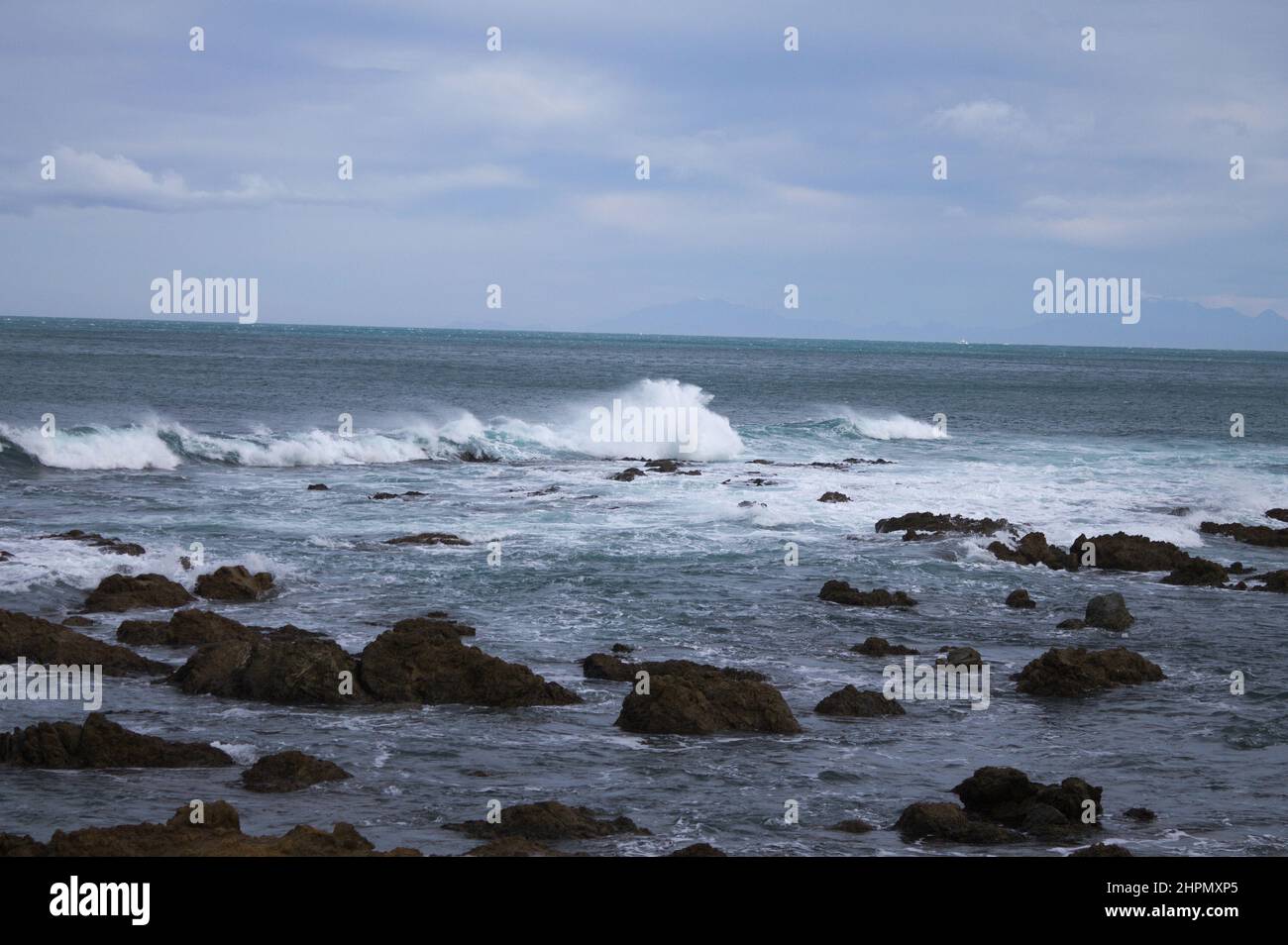 Beautiful shot of sea waves crashing on a rocky shore in New Zealand ...