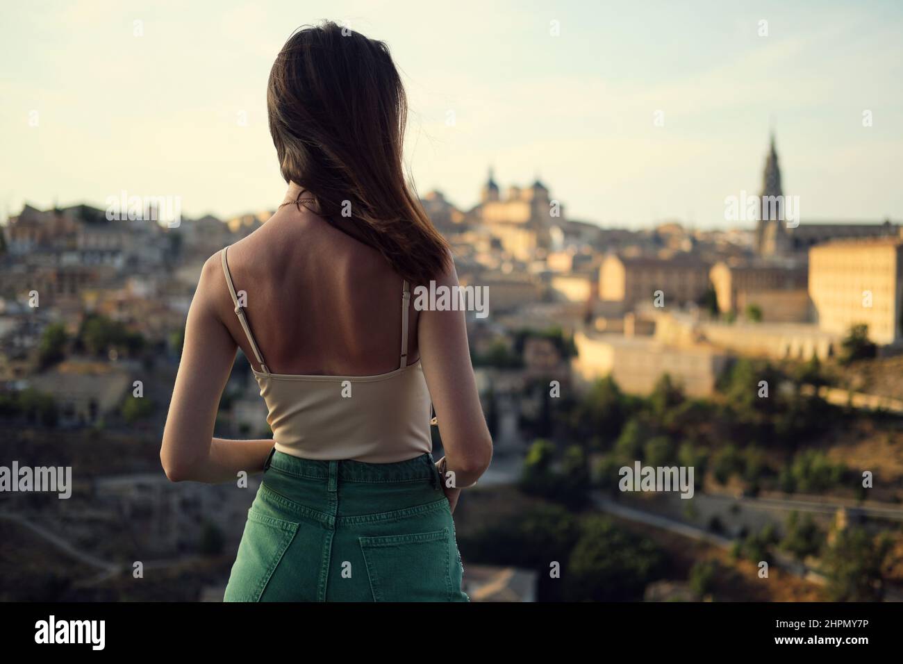 Rear back view, young woman enjoy Toledo cityscape view, from observation deck. Female tourist viewing famous landmarks, city scenery. Travel destinat Stock Photo