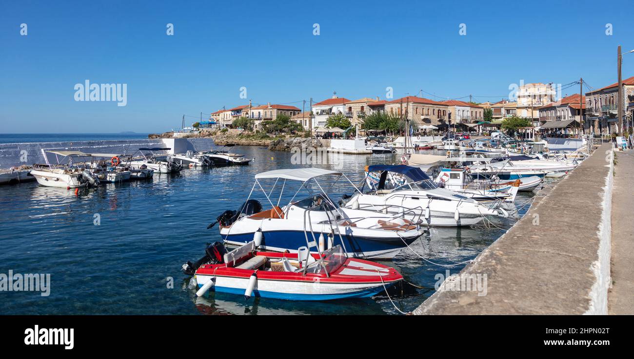 Greece Peloponnese. Mani, Agios Nikolaos traditional fishing village. Boats anchored at harbor, stone buildings background. Sunny summer day Stock Photo