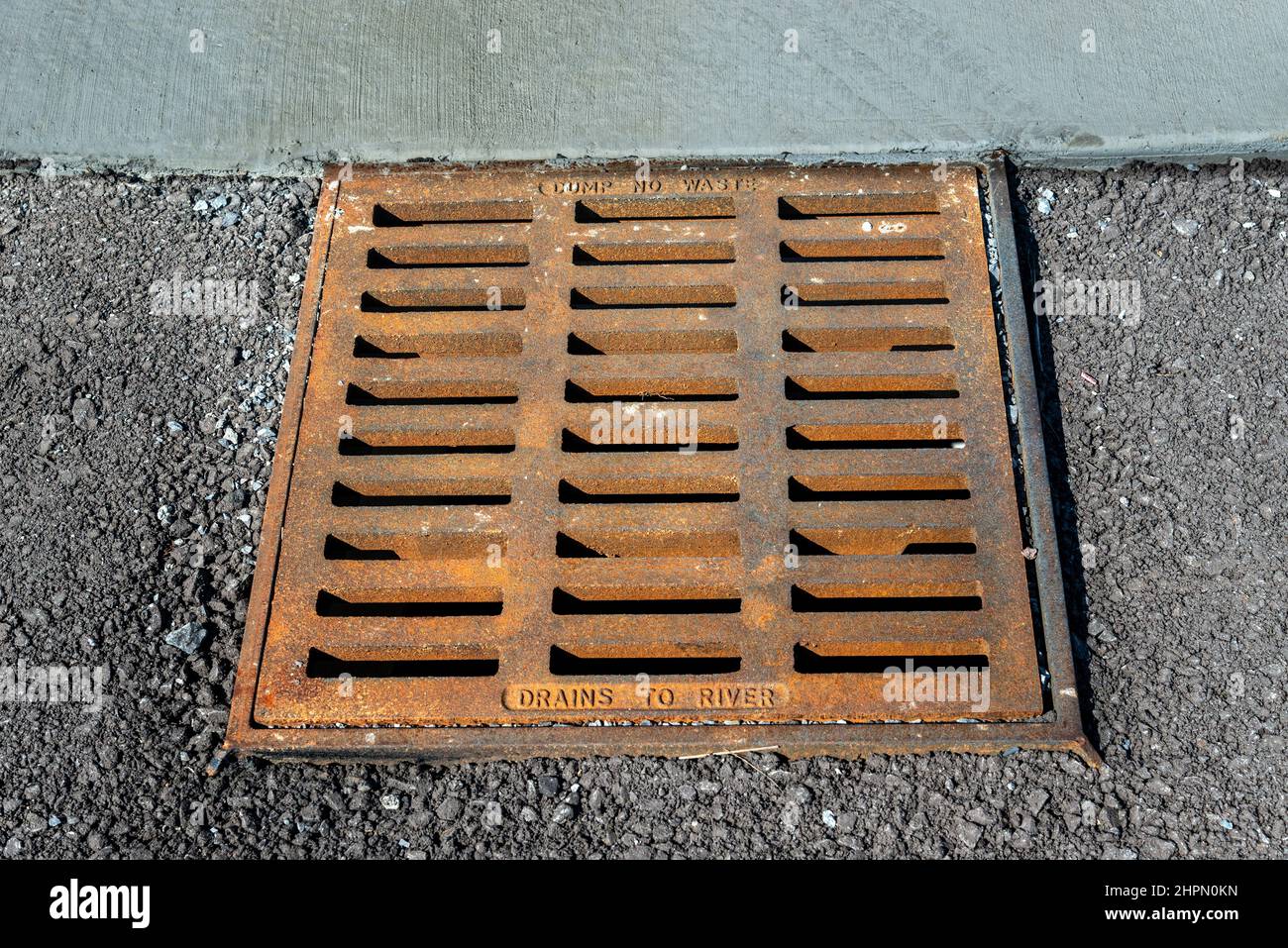 Horizontal shot of a badly rusted sewer grainage grate at a construction site. Stock Photo