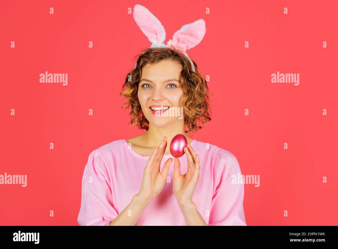 Happy Easter. Smiling girl with pink egg. Spring holiday. Woman in rabbit bunny ears. Hunting eggs. Stock Photo