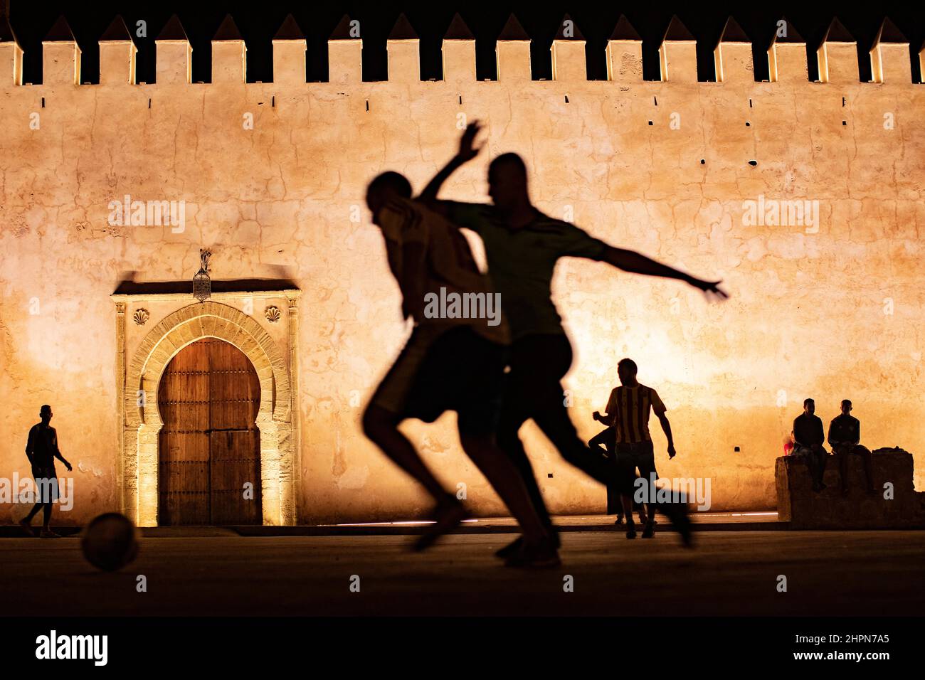 Youth play football at night outside the Kasbah of the Udayas in Rabat, Morocco, North Africa. Stock Photo