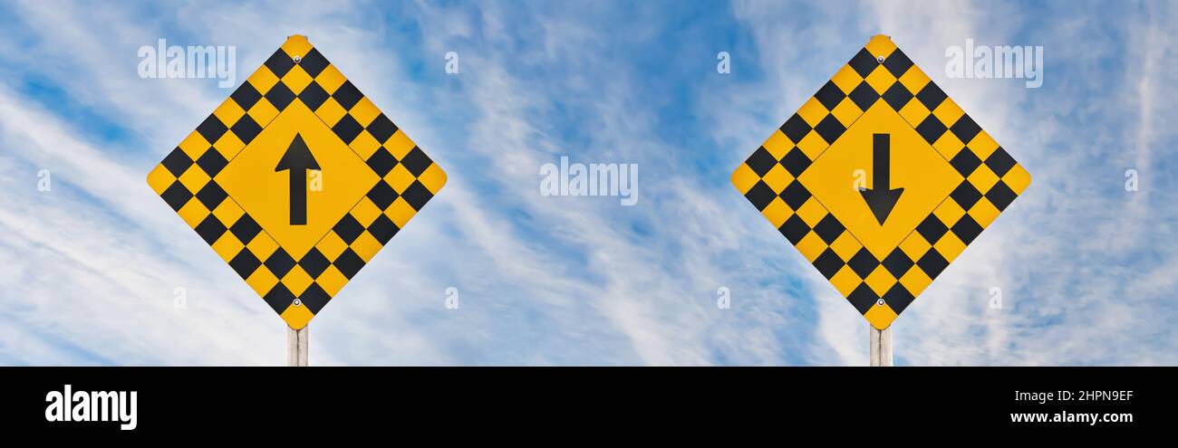 Road Signs with Up and Down Direction Arrows Side by Side Against a dramatic blue sky Stock Photo