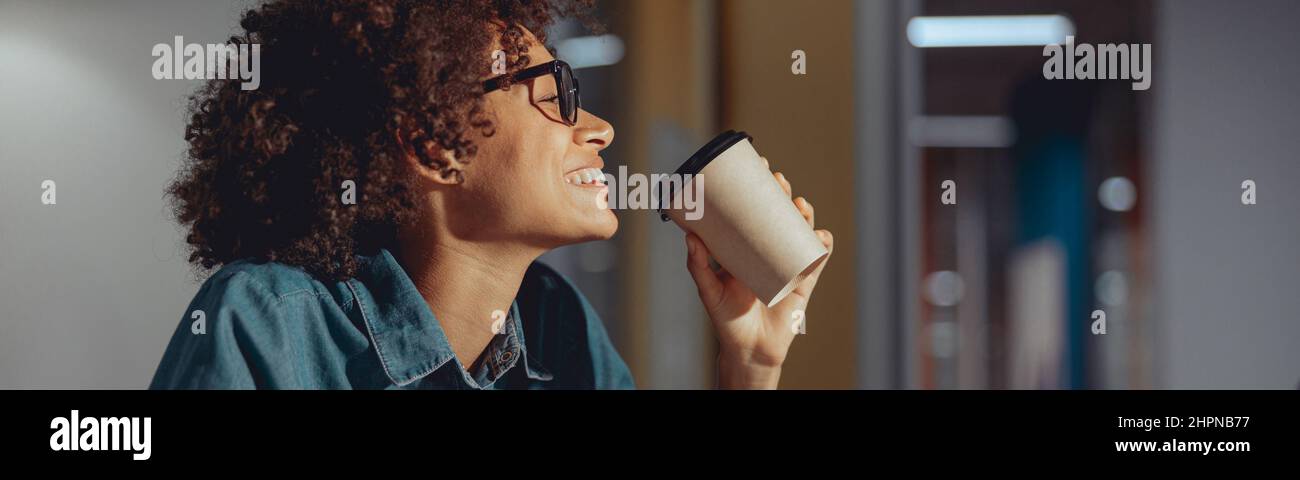 Happy Afro American lady writing at her workplace Stock Photo