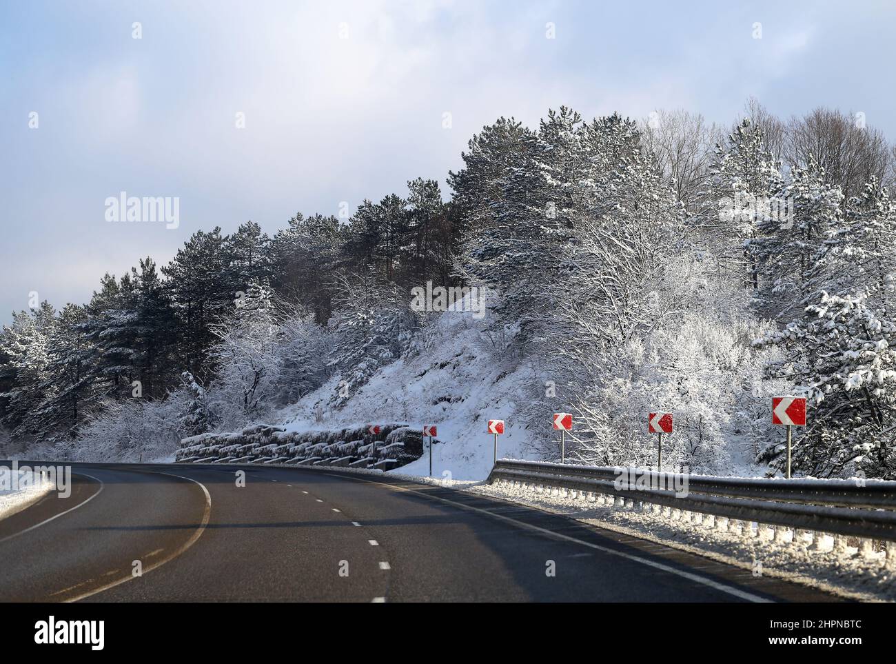 Beautiful winter mountain road with snow-covered trees on the side of the road Stock Photo