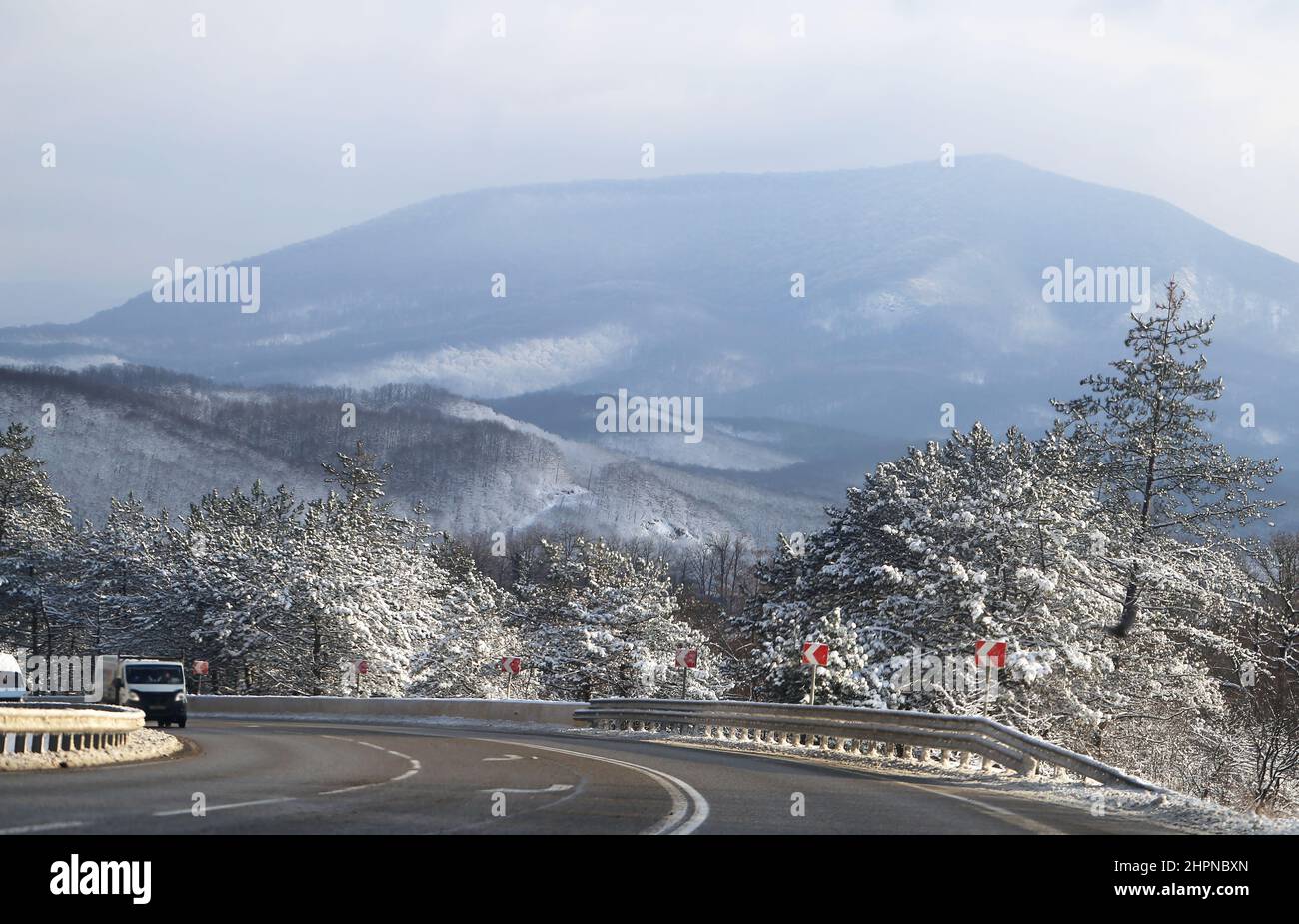 Beautiful winter mountain road with snow-covered trees on the side of the road Stock Photo