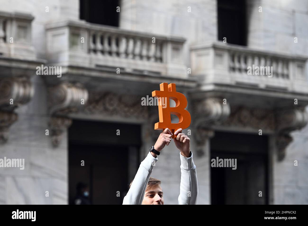 New York, USA. 22nd Feb, 2022. A man holds up a Bitcoin currency emblem (by artist Leonid Sukala) in front of the New York Stock Exchange as the DOW reacts to the news that Russian President Vladimir Putin ordered troops into Ukraine, New York, NY, February 22, 2022. Stocks tumbled as crude oil price surged while the United States and its allies announced economic sanctions against Russia for its incursion into Ukraine. (Photo by Anthony Behar/Sipa USA) Credit: Sipa USA/Alamy Live News Stock Photo