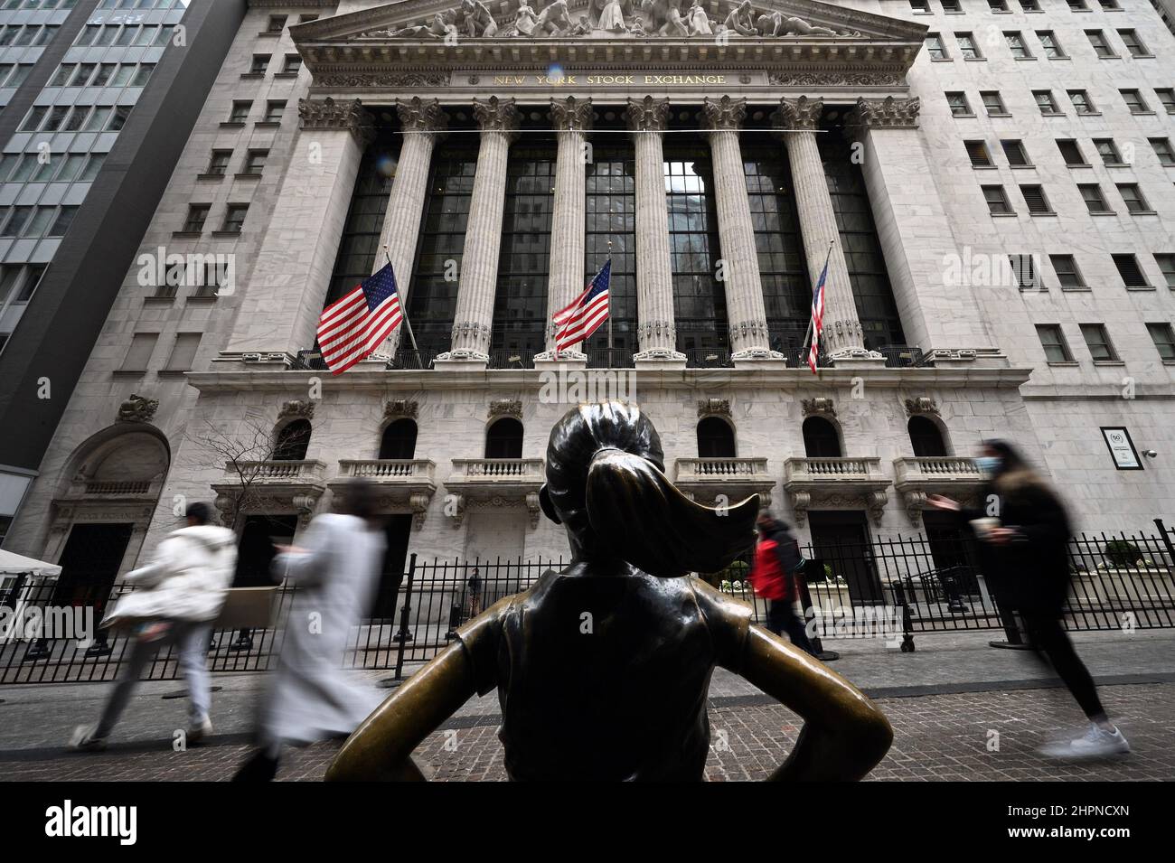 New York, USA. 22nd Feb, 2022. People walk between the “Fearless Girl” bronze statue (by artist Kristen Visbal” and the New York Stock Exchange as the DOW reacts to the news that Russian President Vladimir Putin ordered troops into Ukraine, New York, NY, February 22, 2022. Stocks tumbled as crude oil price surged while the United States and its allies announced economic sanctions against Russia for its incursion into Ukraine. (Photo by Anthony Behar/Sipa USA) Credit: Sipa USA/Alamy Live News Stock Photo