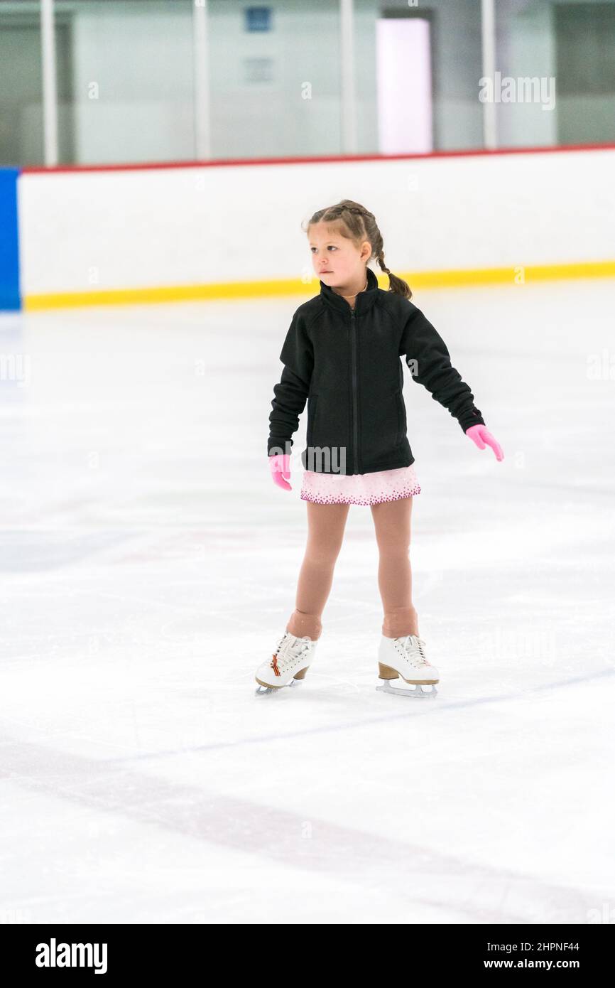 Little girl practicing figure skating on an indoor ice skating rink