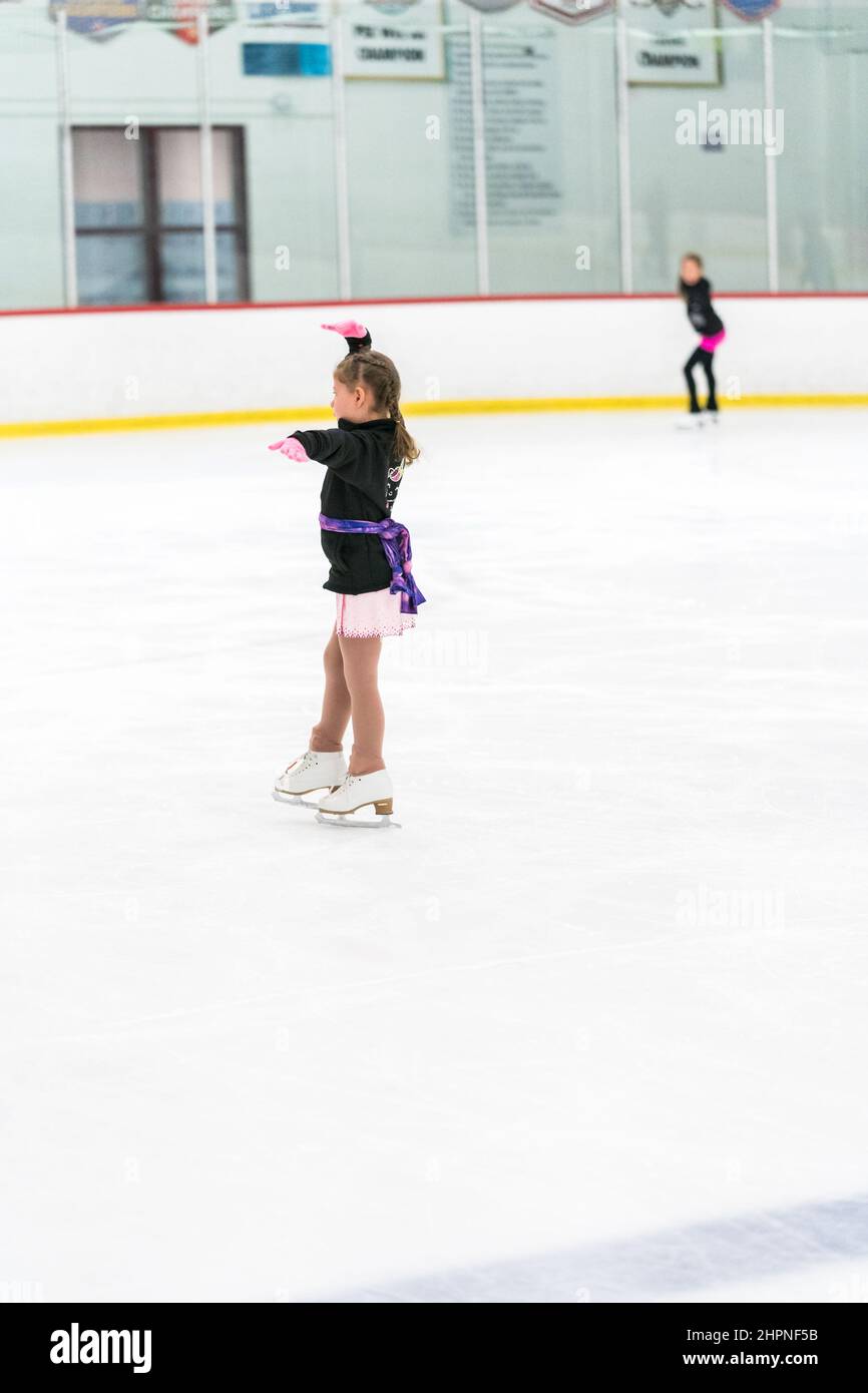 Little girl practicing figure skating on an indoor ice skating rink