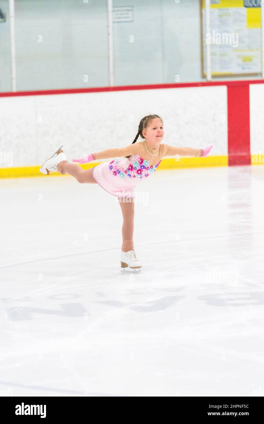 Little girl practicing figure skating on an indoor ice skating rink