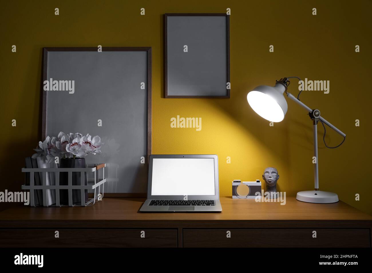 Modern workplace with laptop and glowing lamp in dark office Stock
