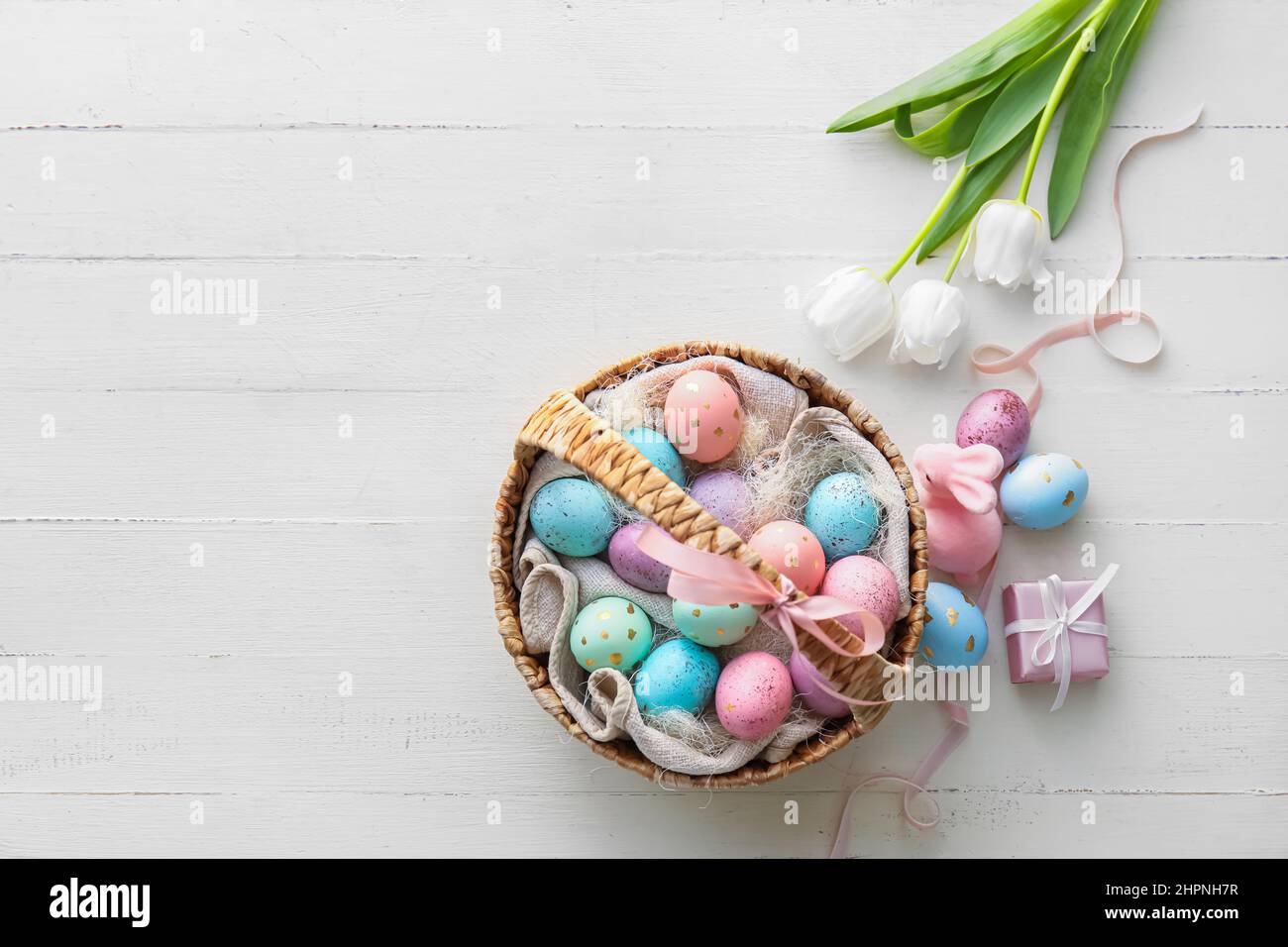 Basket with painted Easter eggs, tulip flowers and bunny on light ...