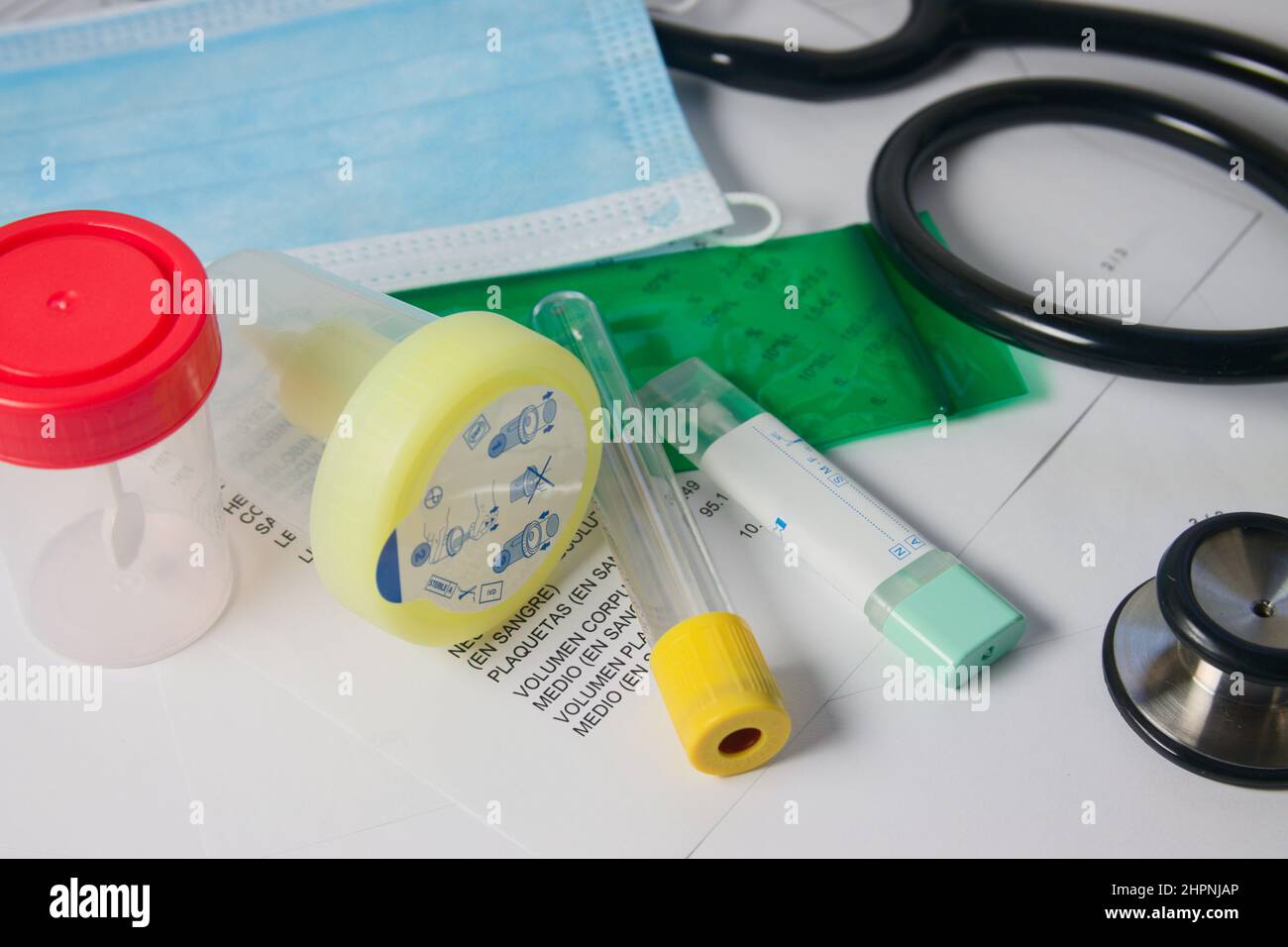 Close-up of a table on which there are several tubes for blood and stool tests next to a stethoscope and a mask Stock Photo